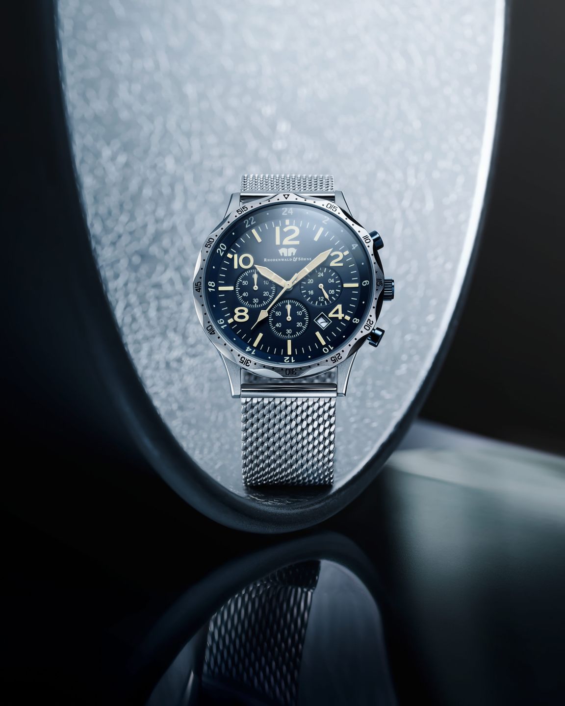 a watch with a blue dial sitting on a silver surface photographed by swiss professional watch photographer