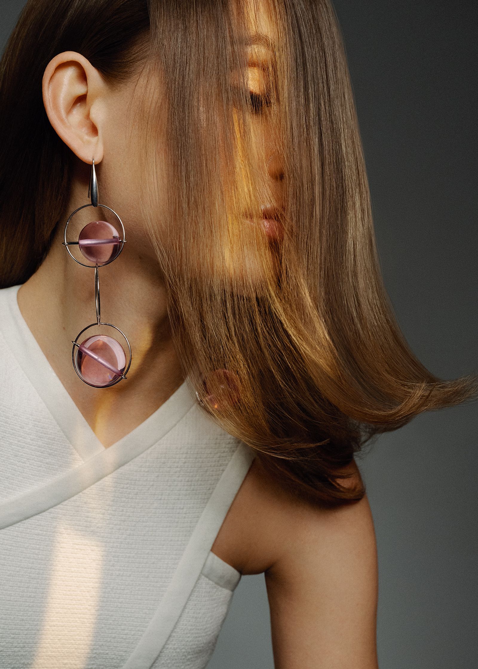 a woman with long hair wearing pink earrings