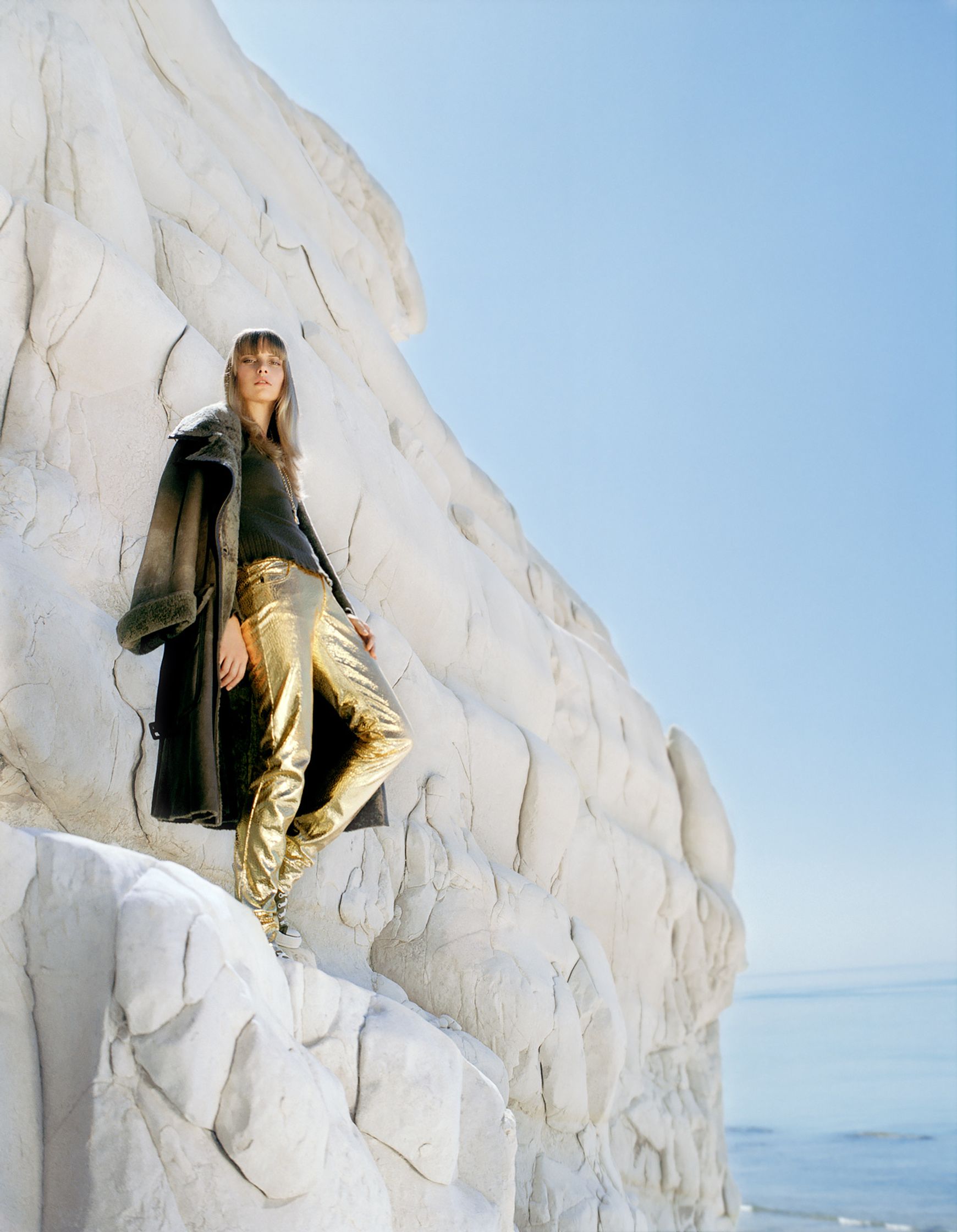 a woman in gold pants standing on top of a cliff editorial retouching hamburg