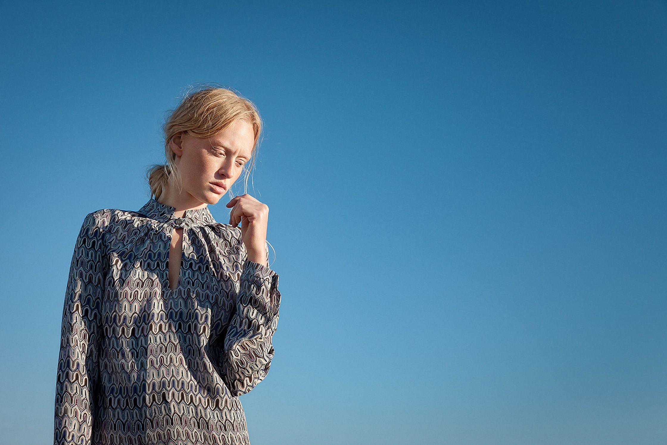 a woman is standing on a beach with her hand on her chin retouche advertising campaign