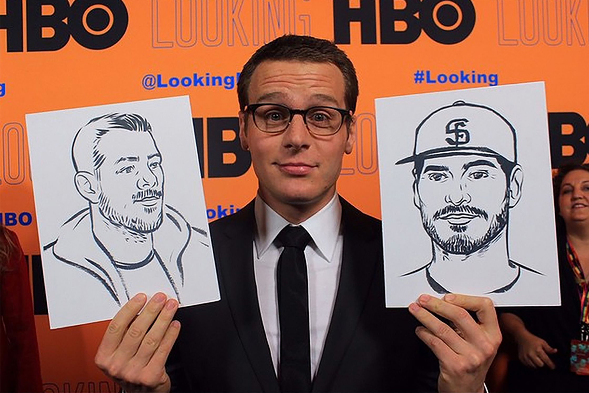 jonathan groff holding up illustrations by Paul Tuller of his Looking Season 2 cast members. HBO