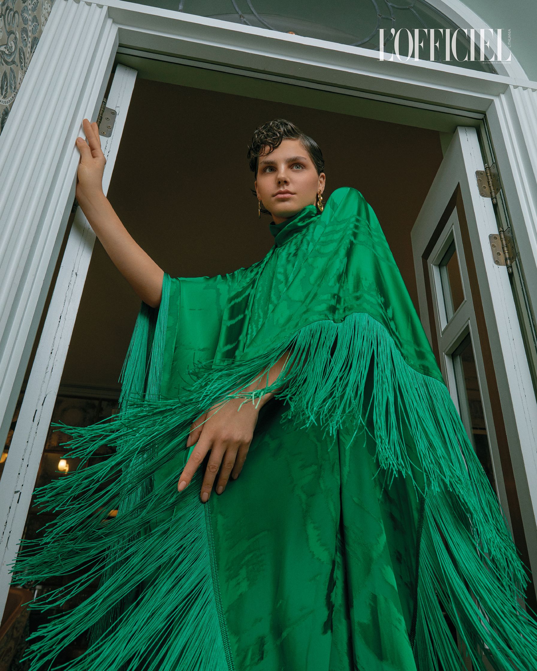 a woman in a green poncho posing in front of a door