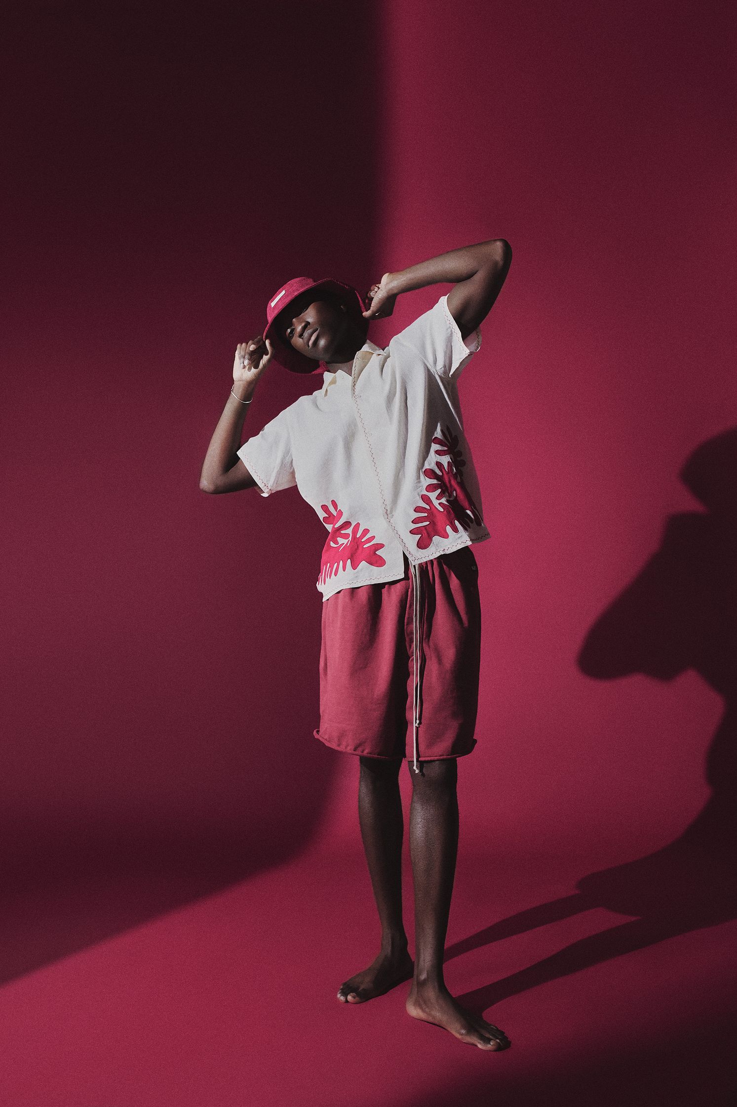 a man in a red shirt and shorts posing in front of a red background