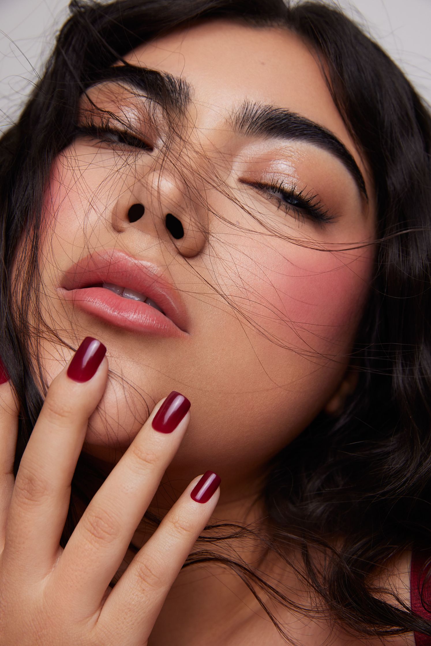 a woman with red nails posing with her hands on her face