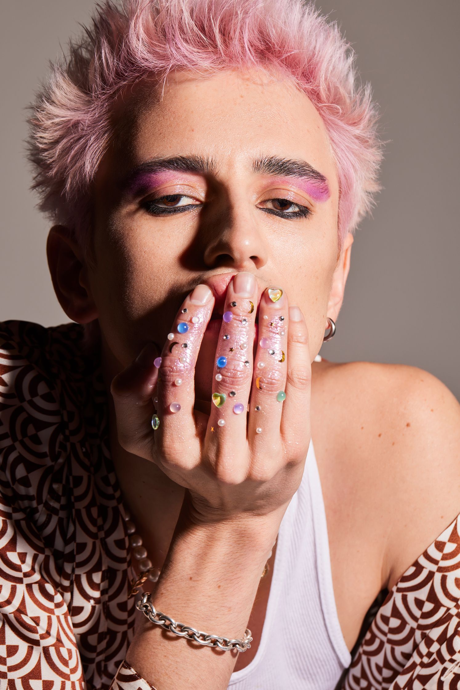 a woman with pink hair is posing with her hands on her face