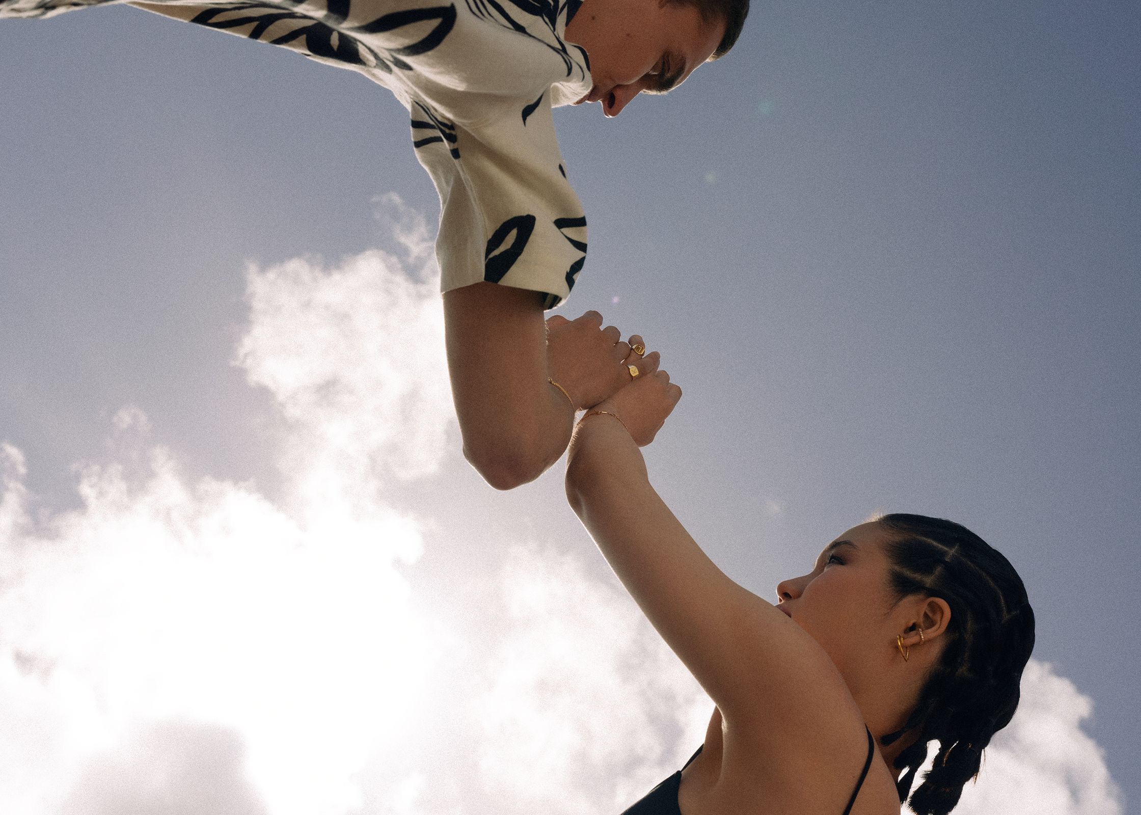 a man and woman reaching for each other in the sky