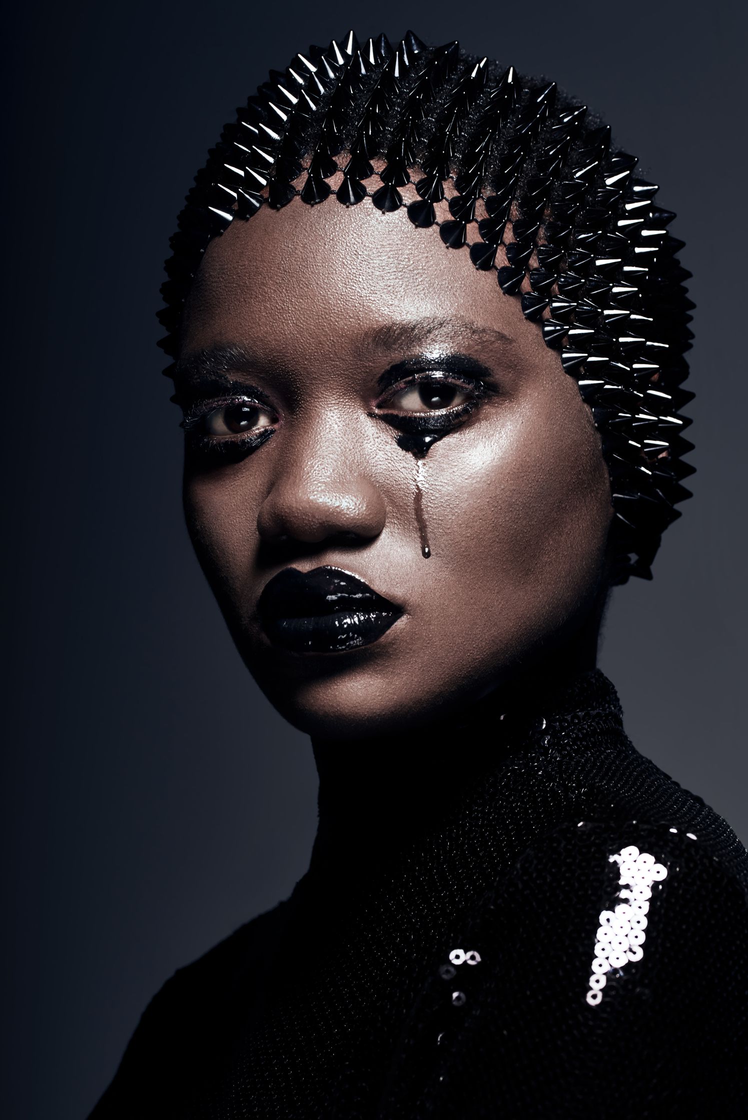 Beauty portrait with model in spiked headpiece and black makeup, symbolizing bold fashion and emotional expression