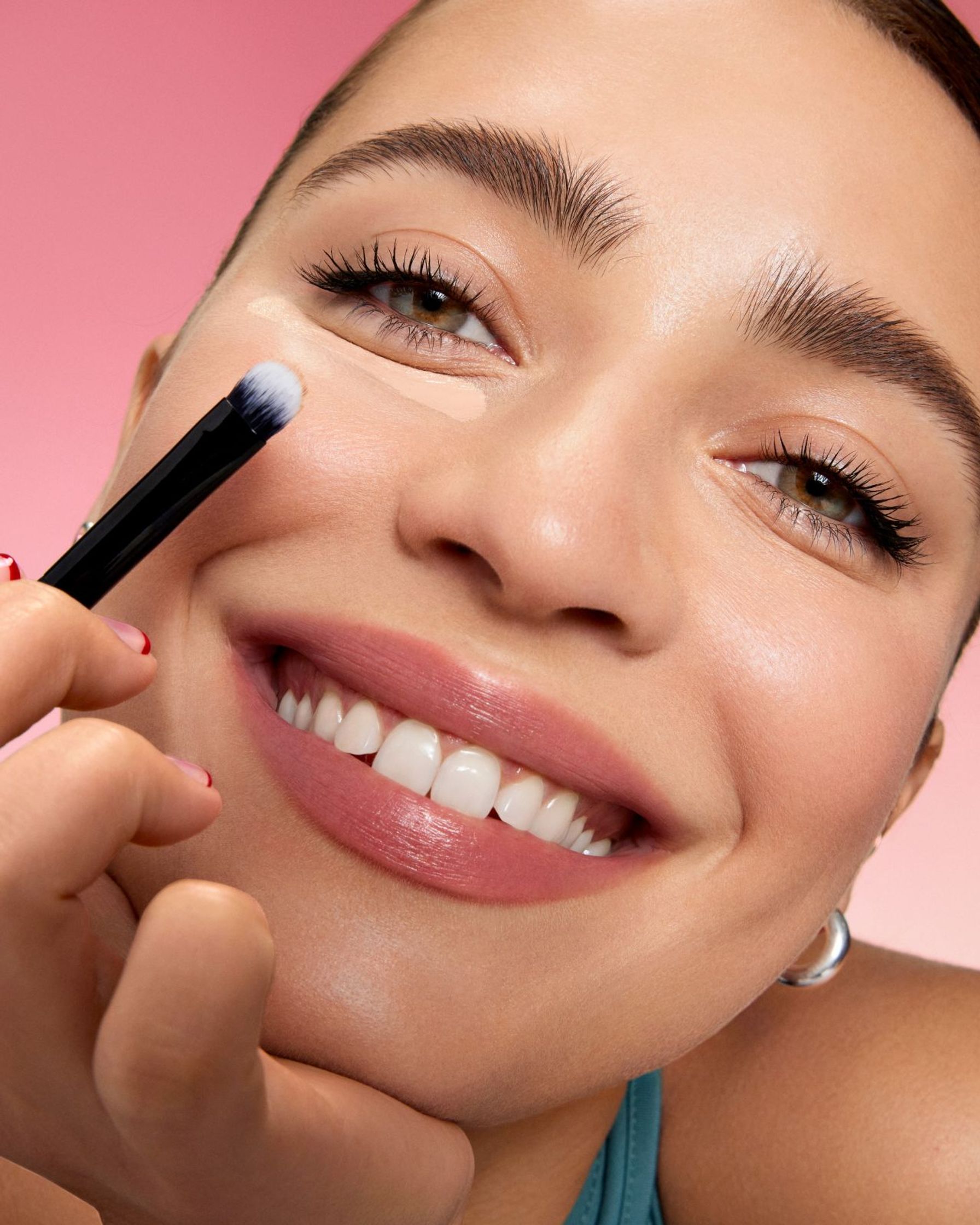 a woman is smiling while holding a makeup brush