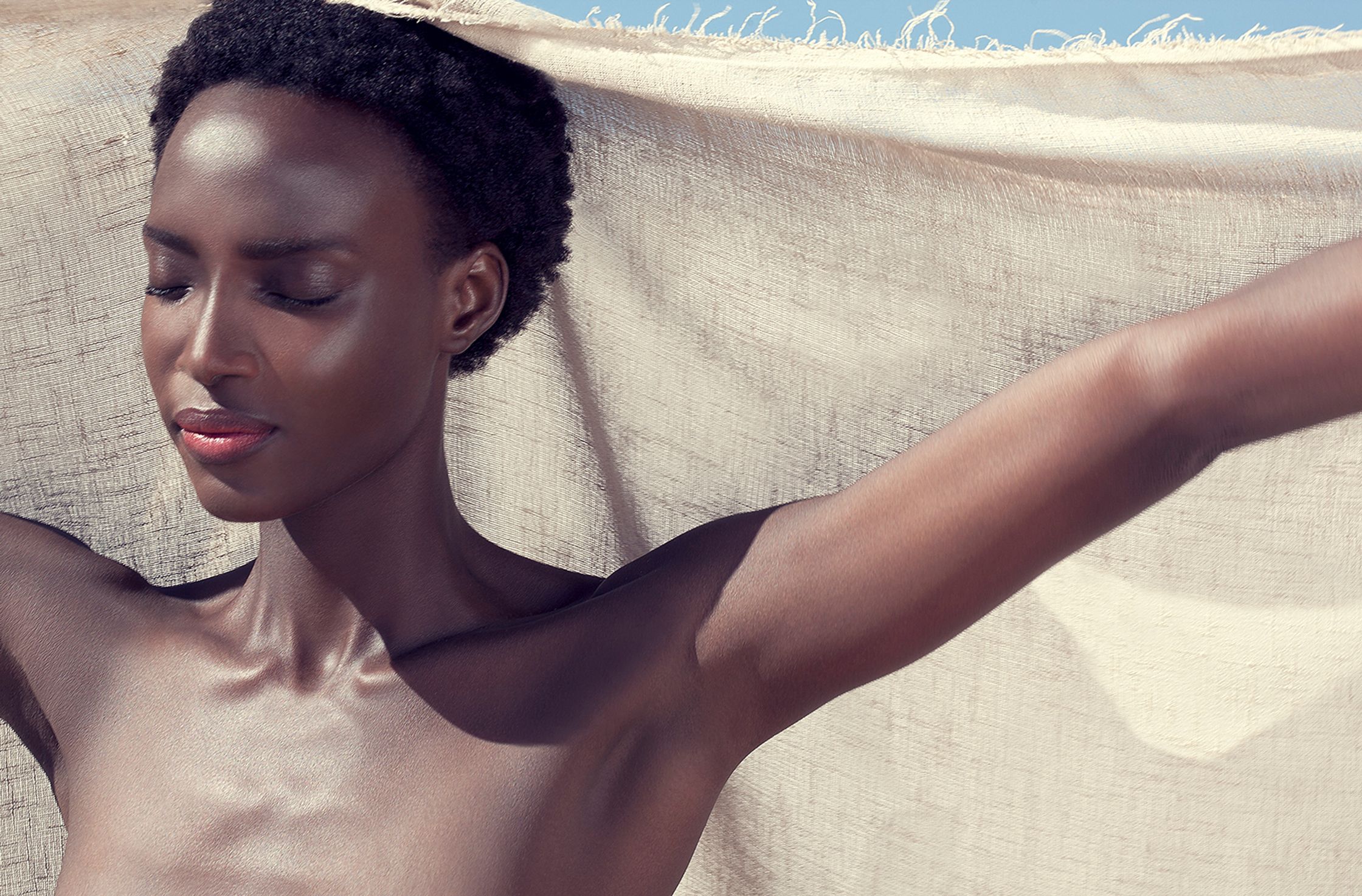 a black woman laying on a towel with her arms outstretched skin retouch