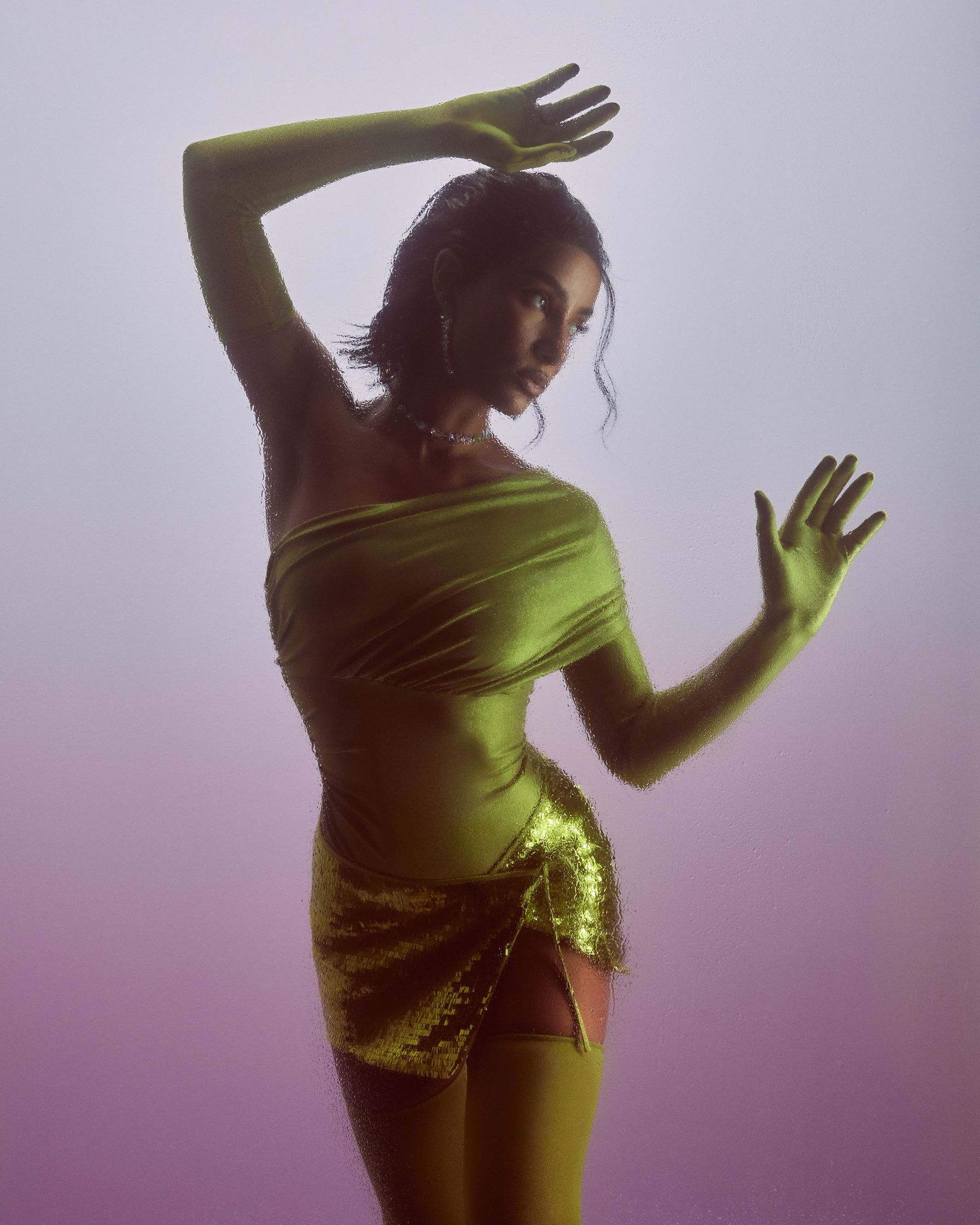 a woman in a green dress posing in front of a purple background