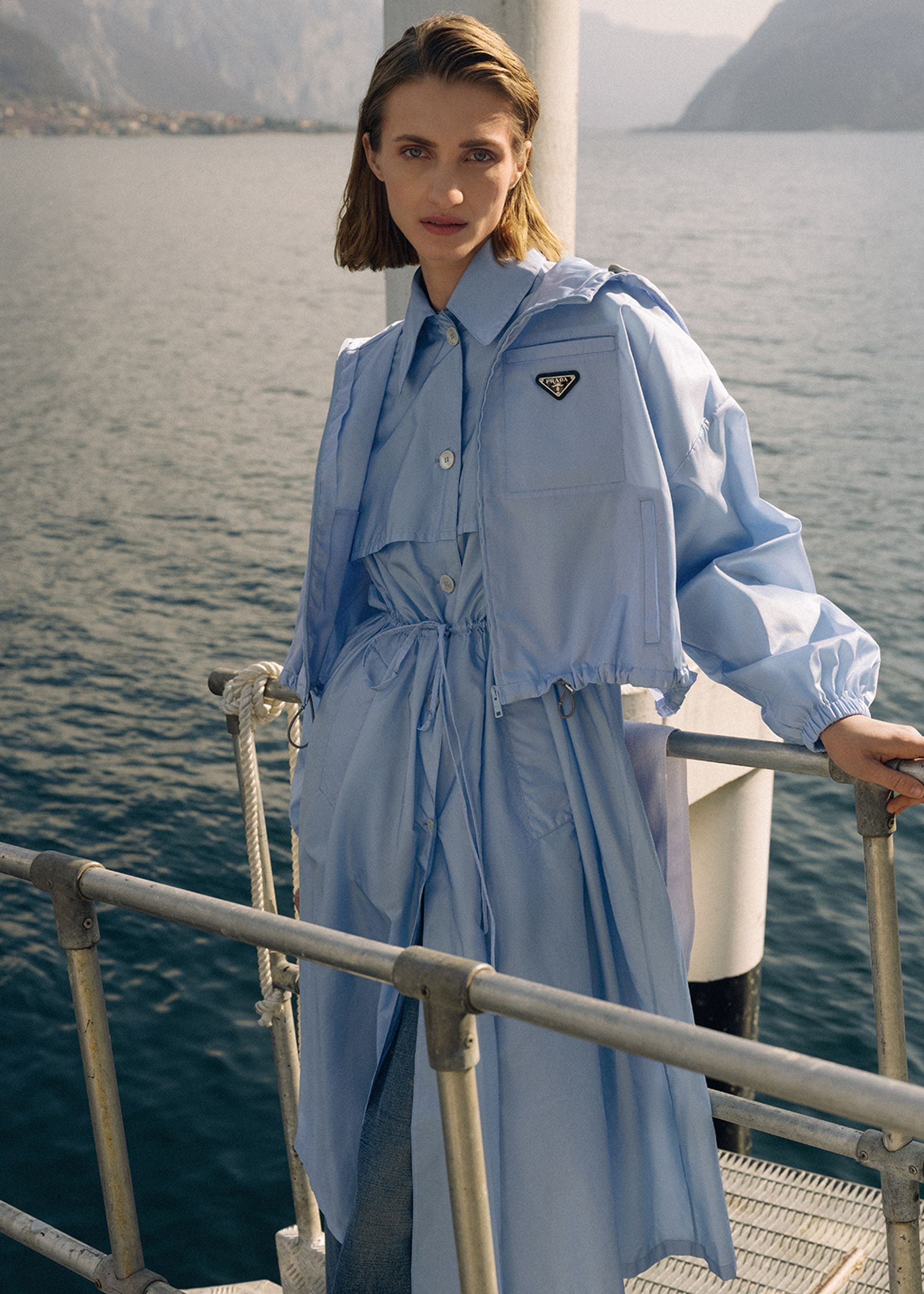 a woman in a blue trench coat standing on a boat