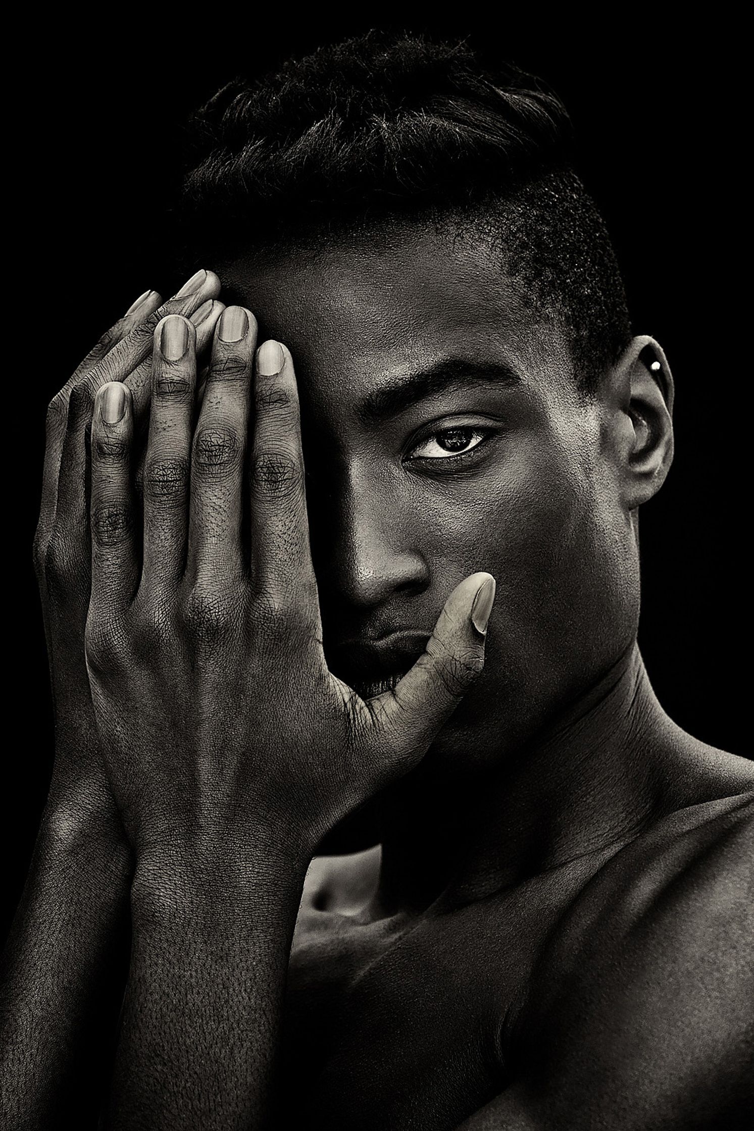 a black and white photo of a man with his hands covering his face portrait retusche