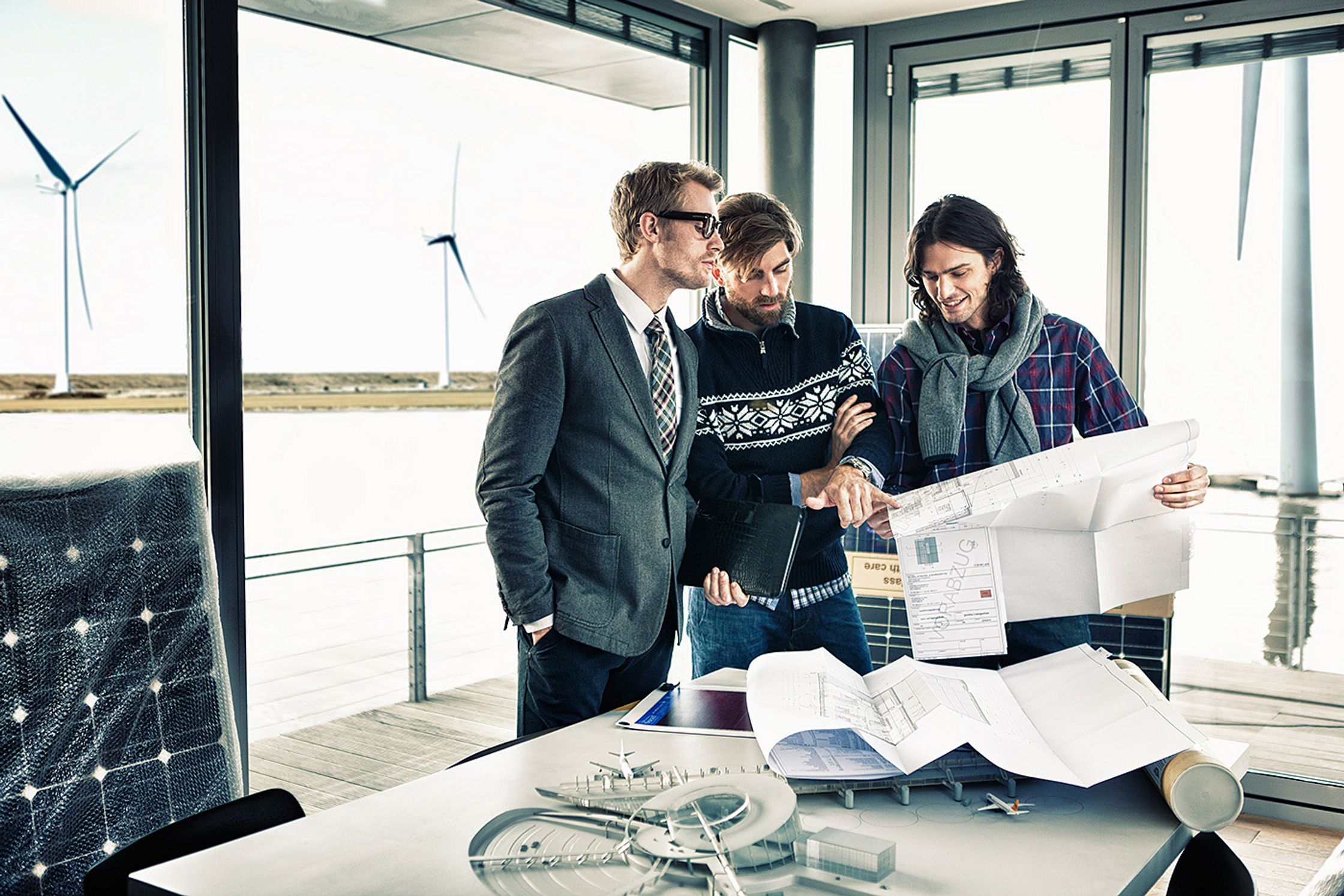 a group of people standing around a table looking at plans Bildbearbeitung calamar fashion kampagne