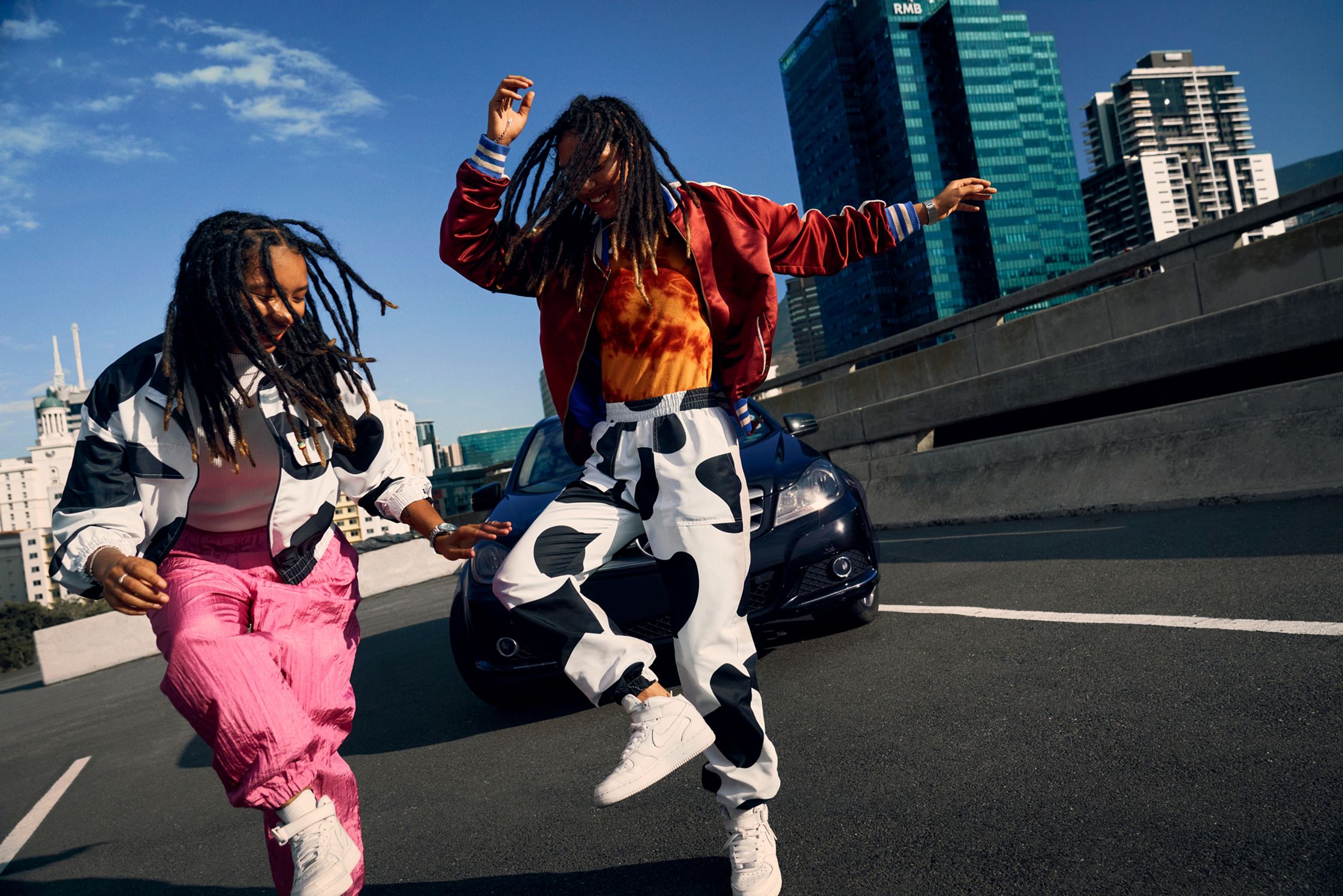 two women with dreadlocks dancing on a city street