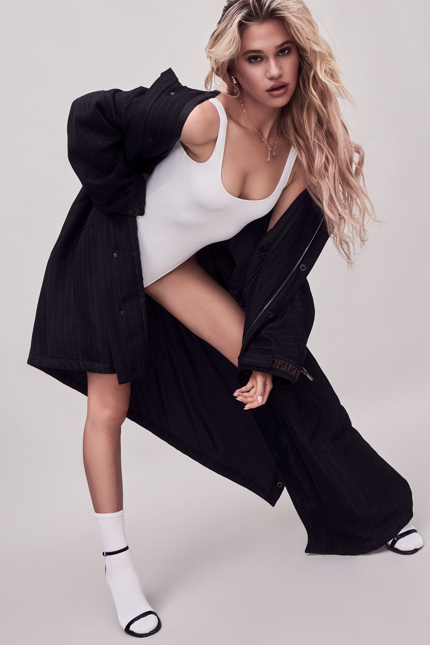 a woman in a black coat and white socks posing for a photo shoot