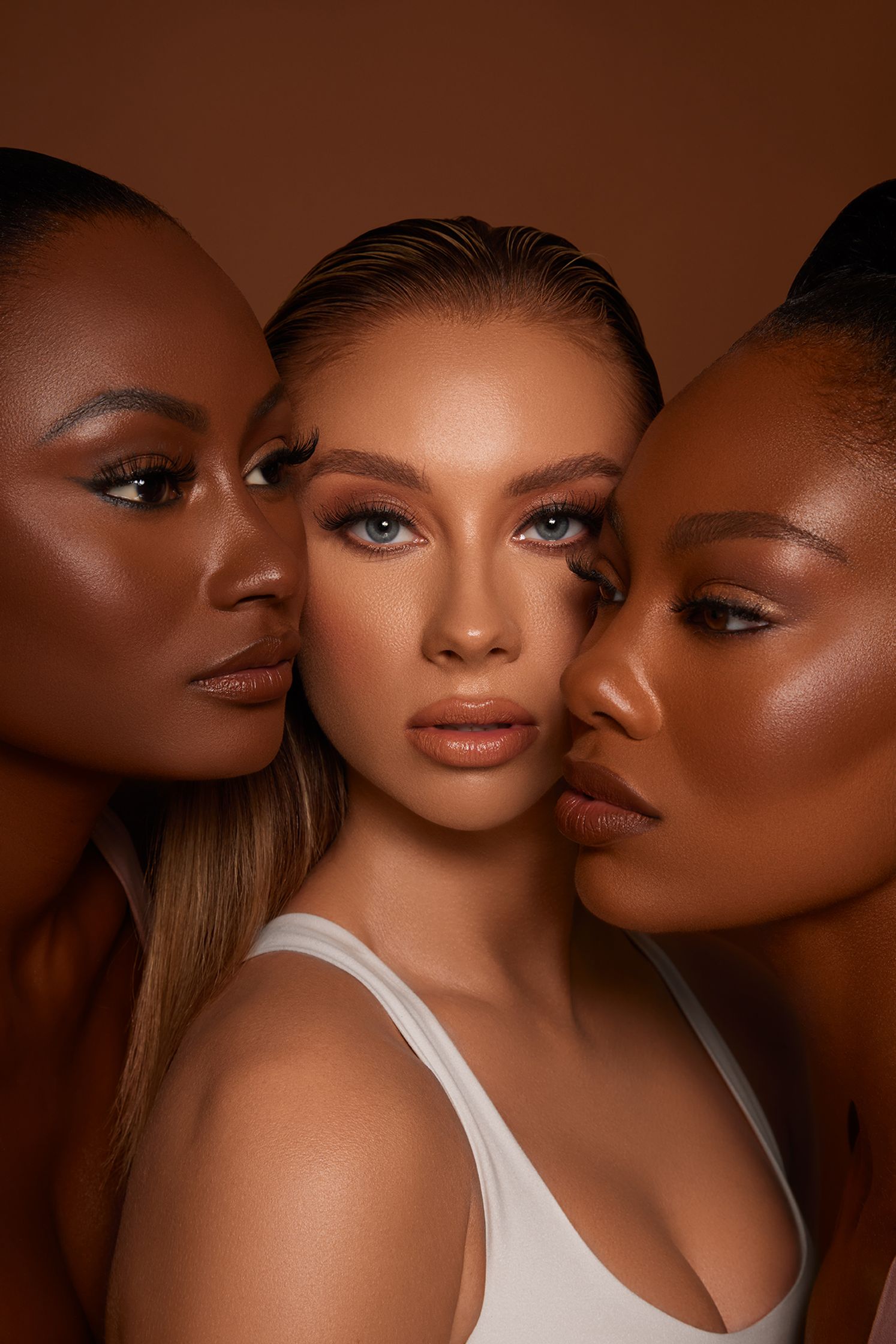 three women posing in front of a brown background