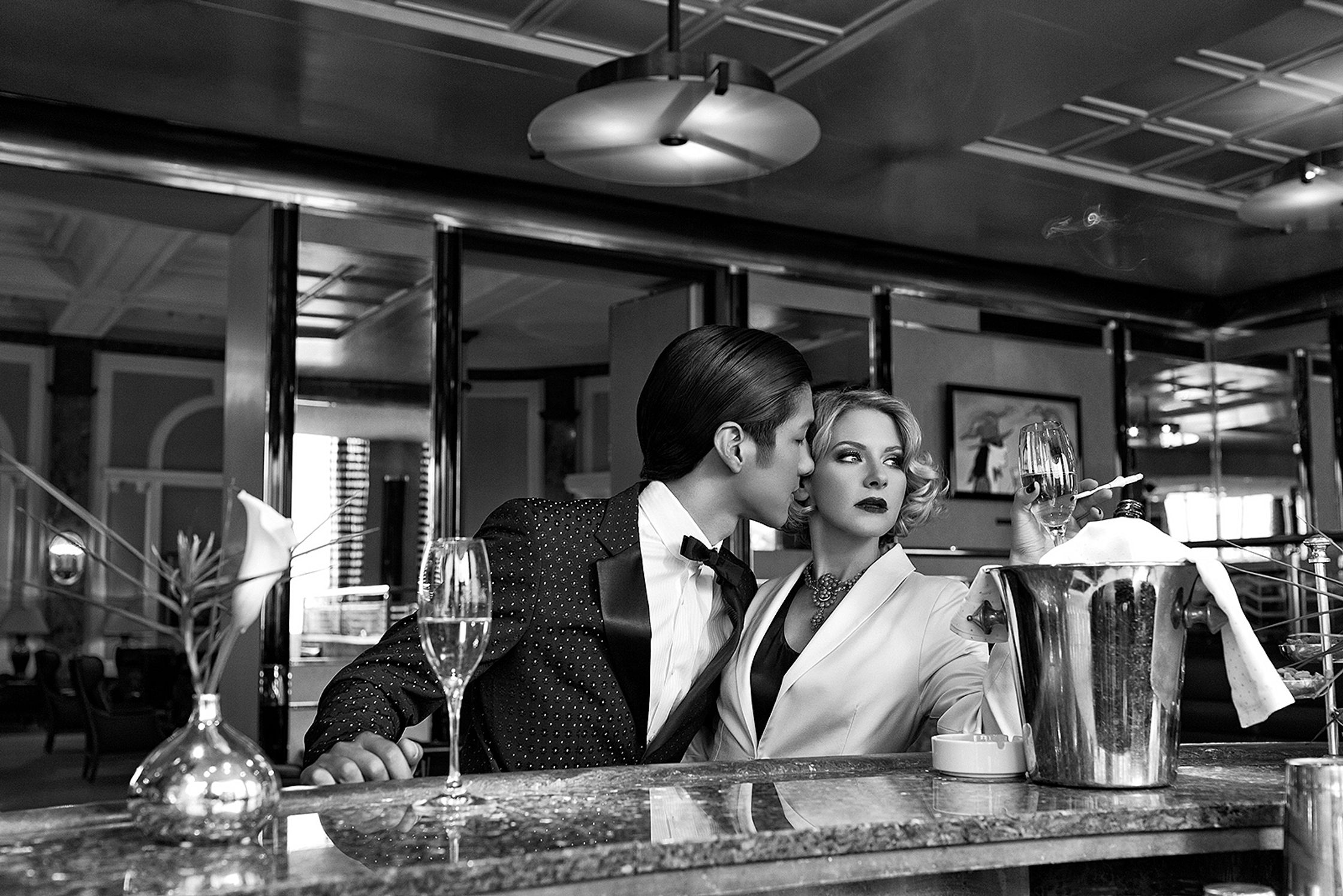 a black and white photo of a couple kissing at a bar advertising retouch hamburg