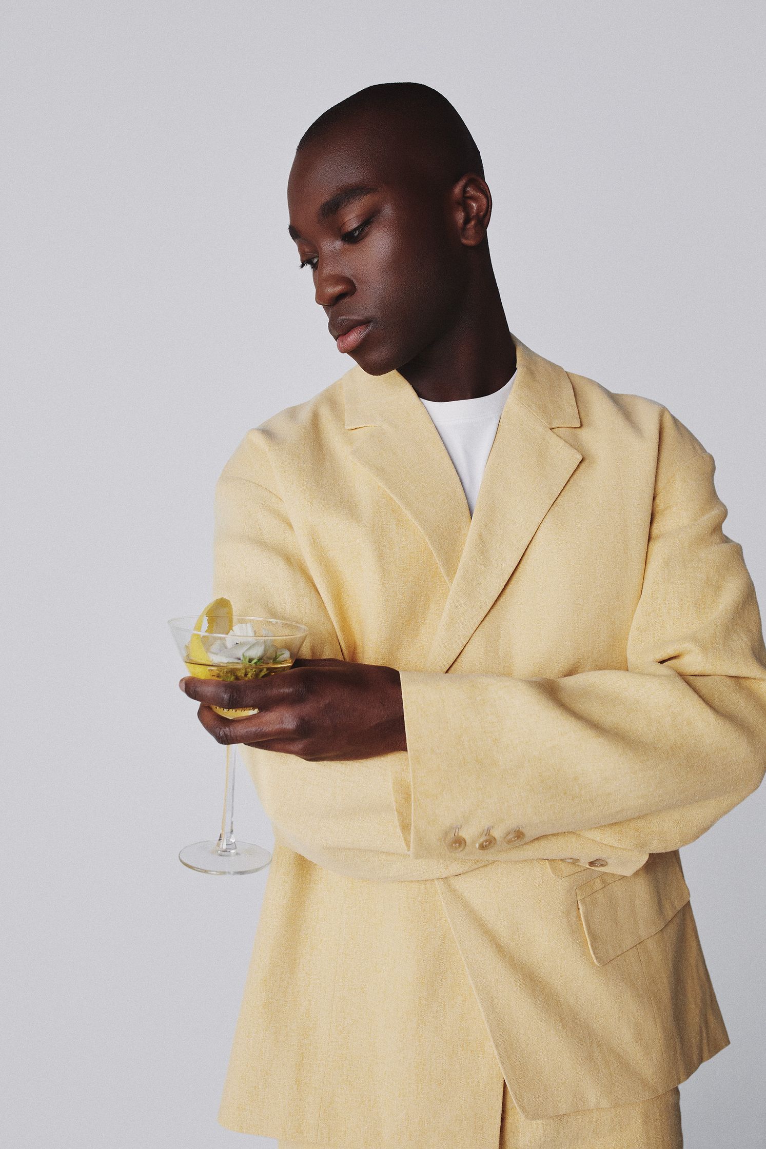 a man in a yellow suit holding a drink