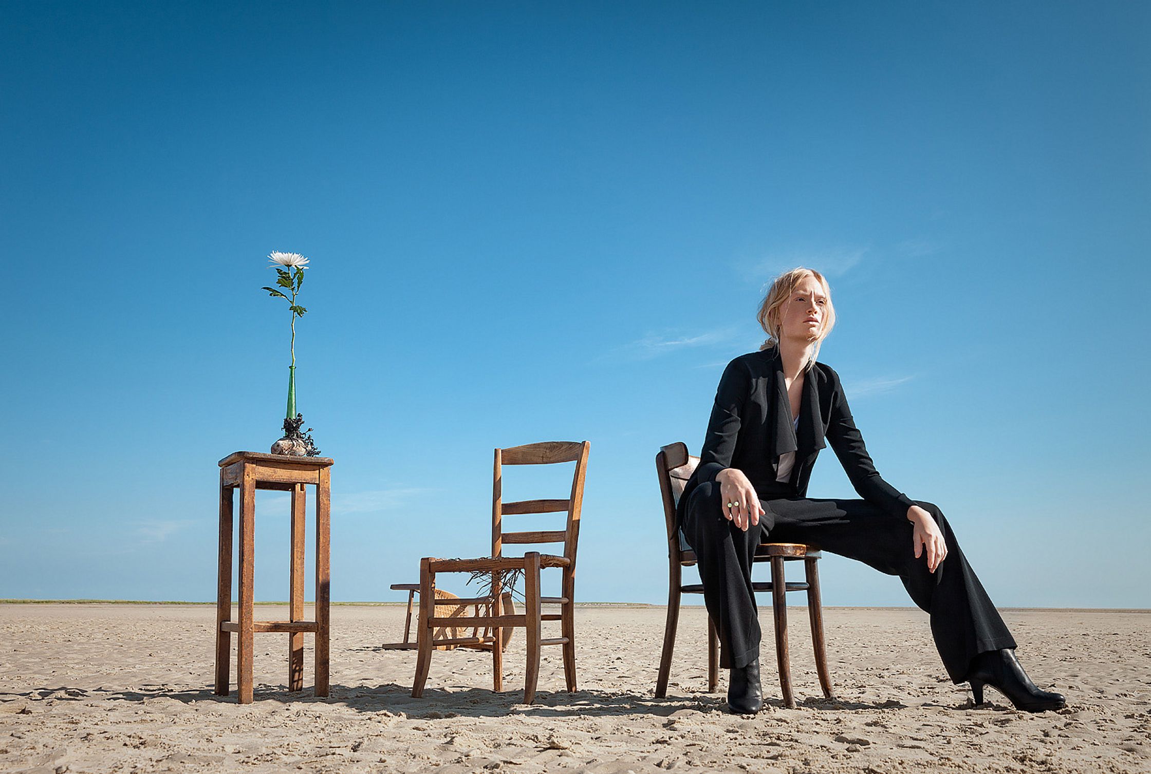 a woman sitting on a chair in the desert retouche advertising campaign