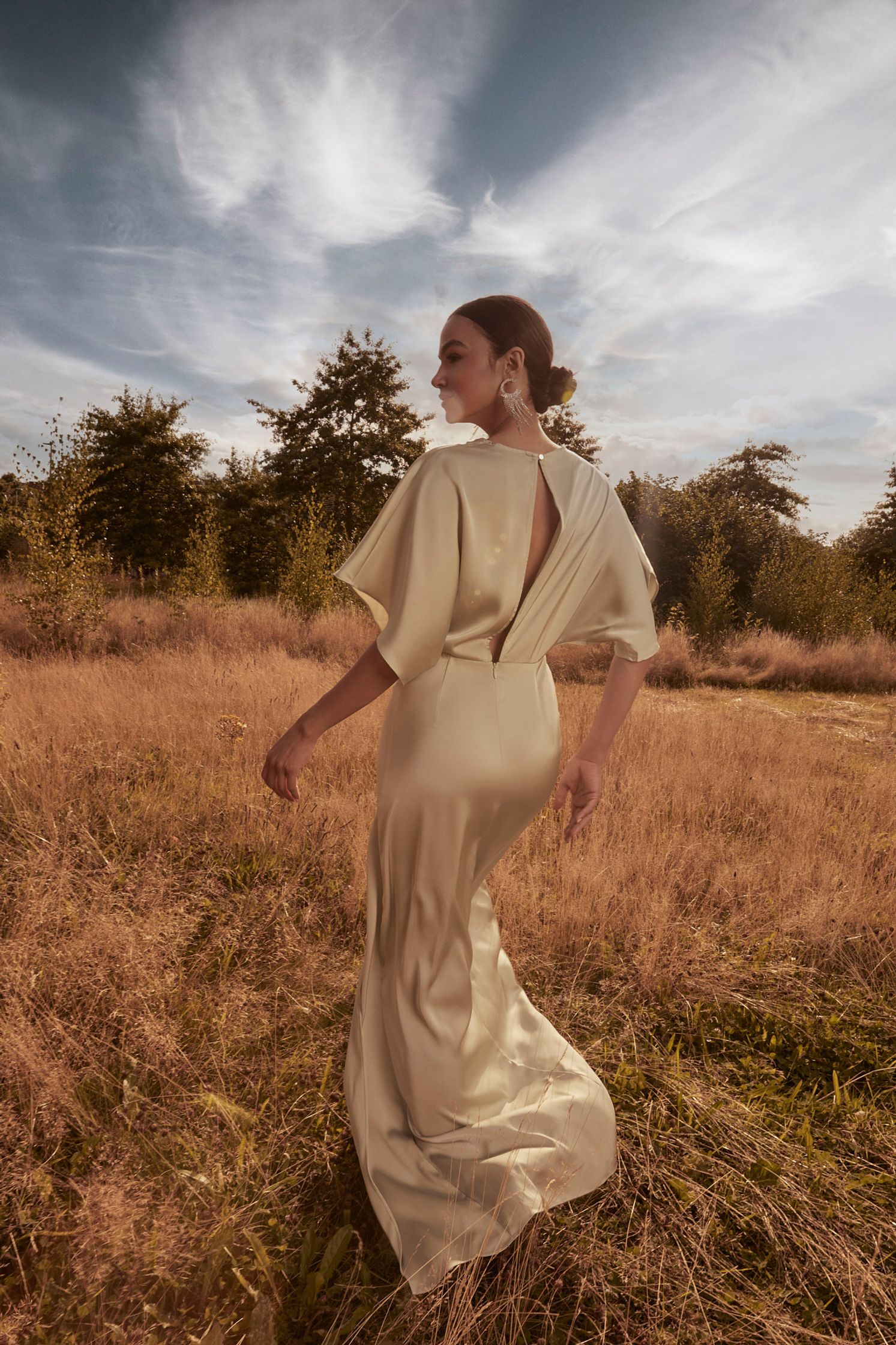 a woman in a white dress standing in a field