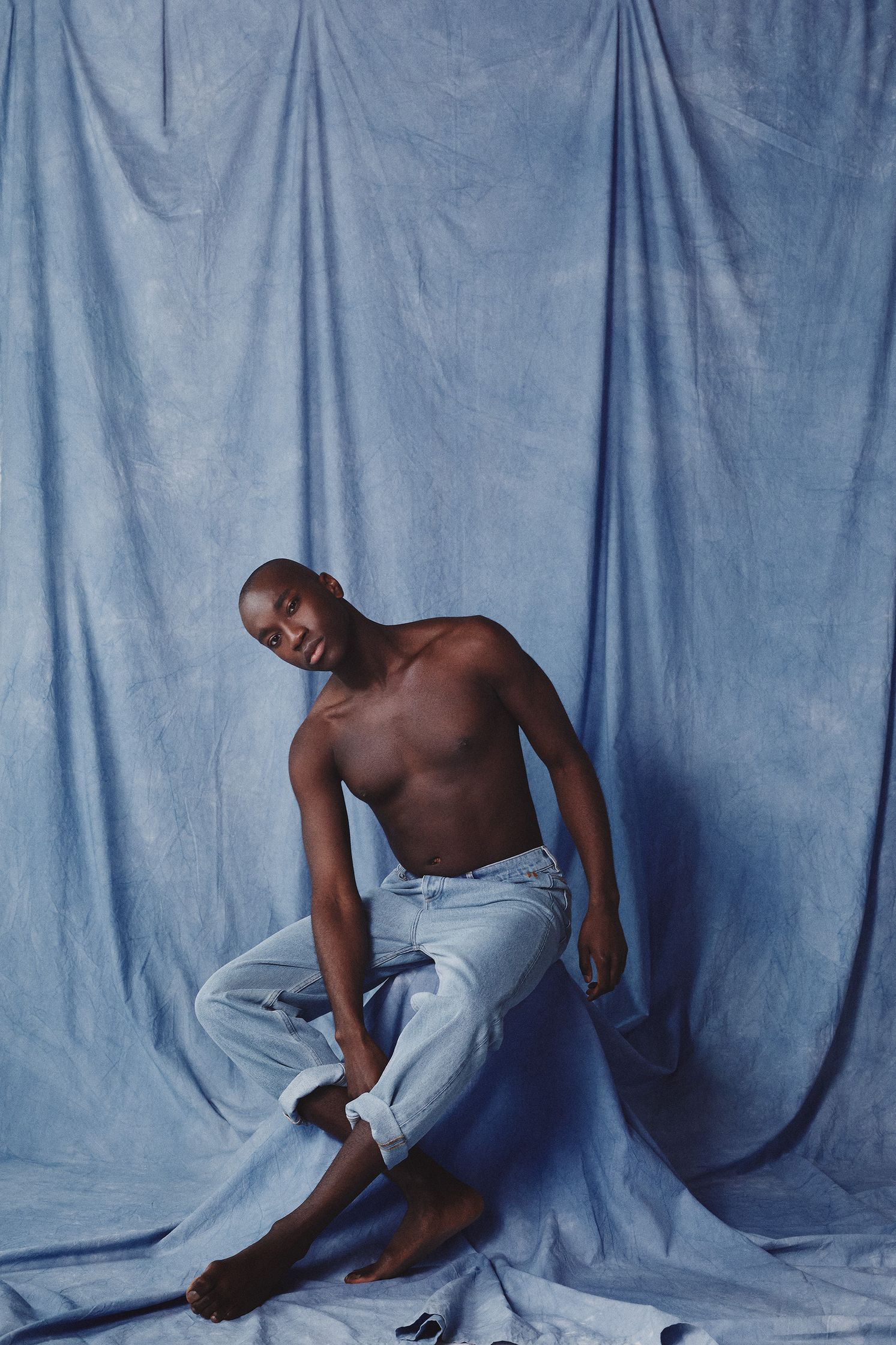 a black man sitting on a blue background