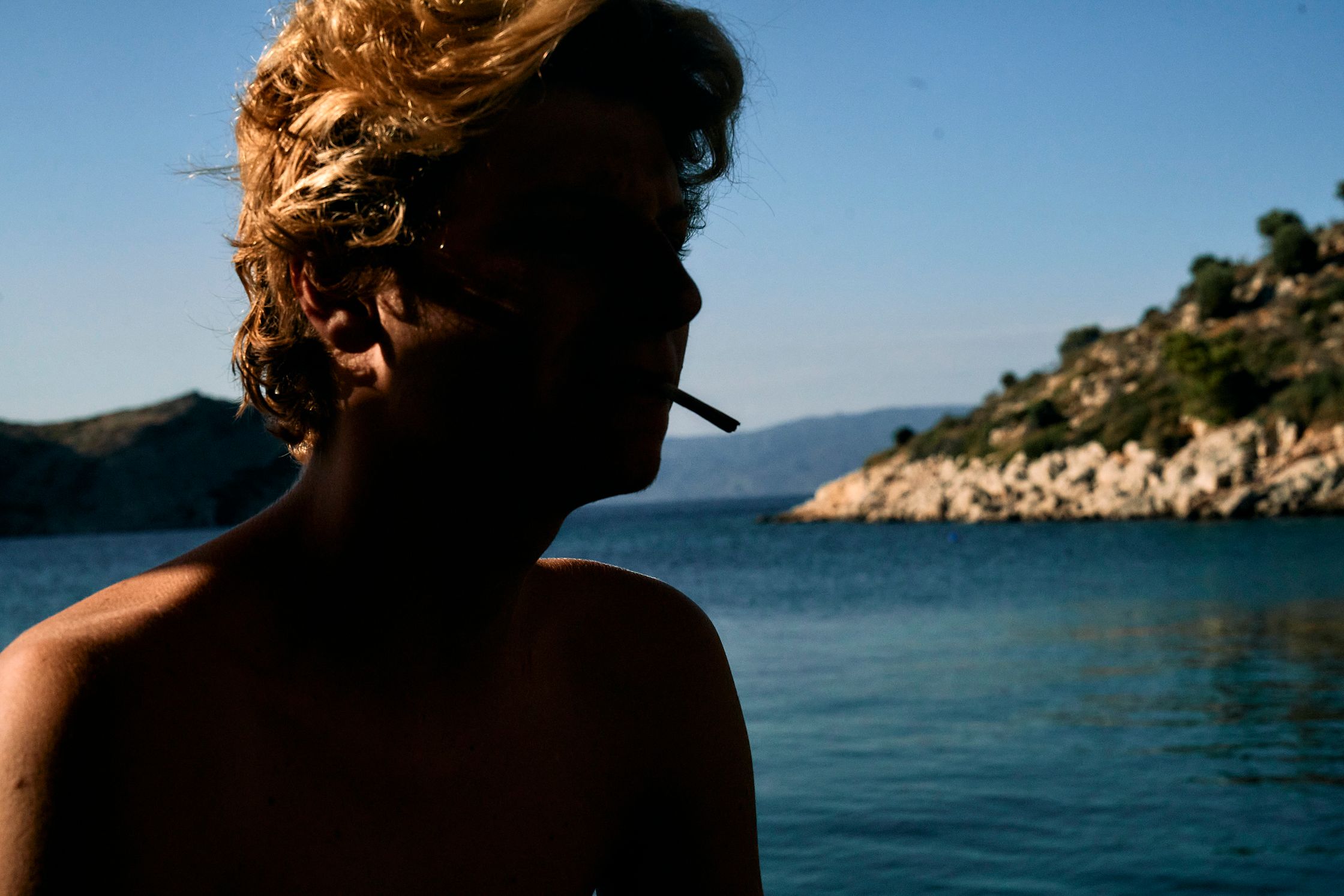 a man smoking a cigarette in front of a body of water