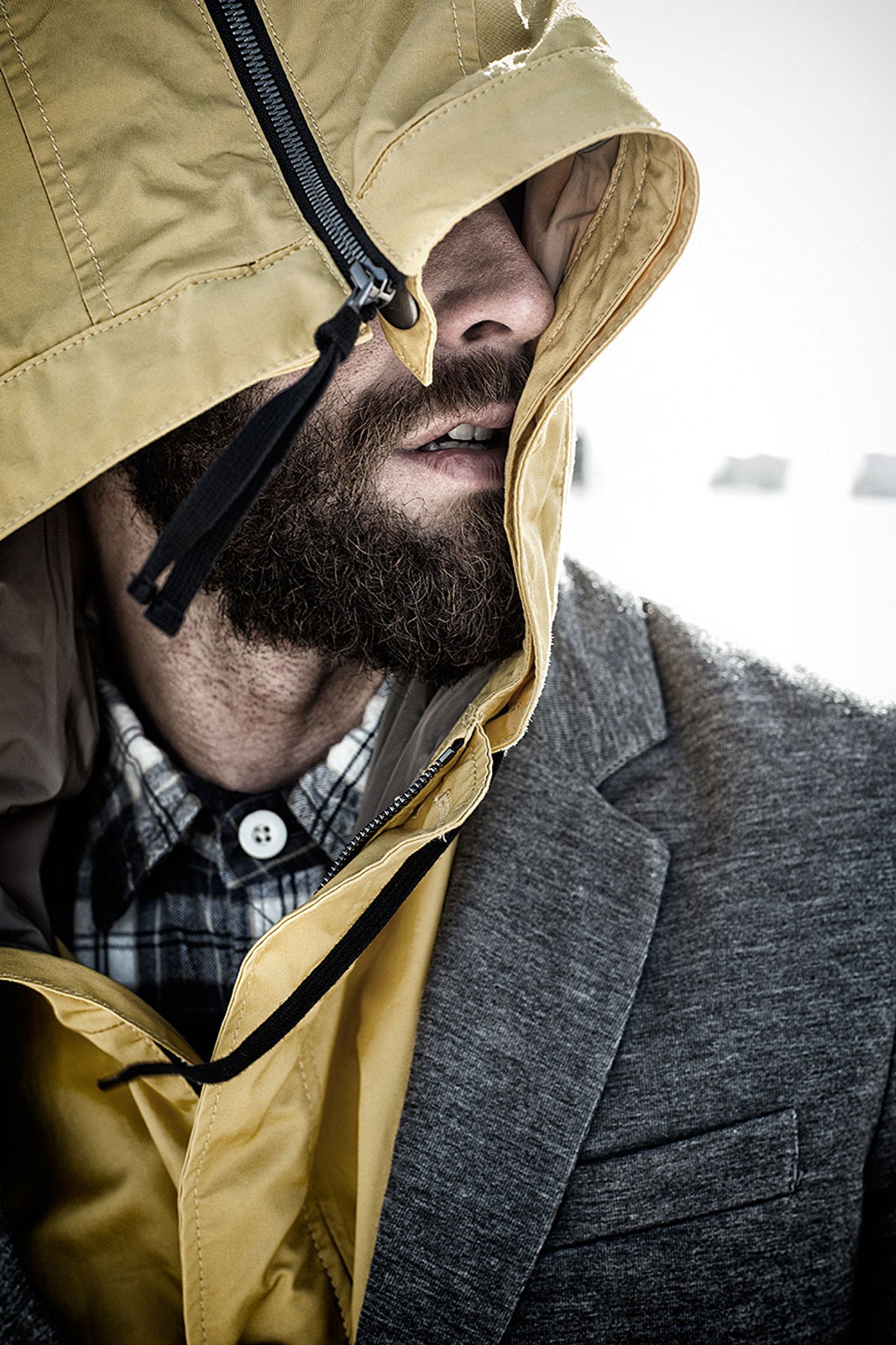 a bearded man in a yellow hooded jacket post production Hamburg