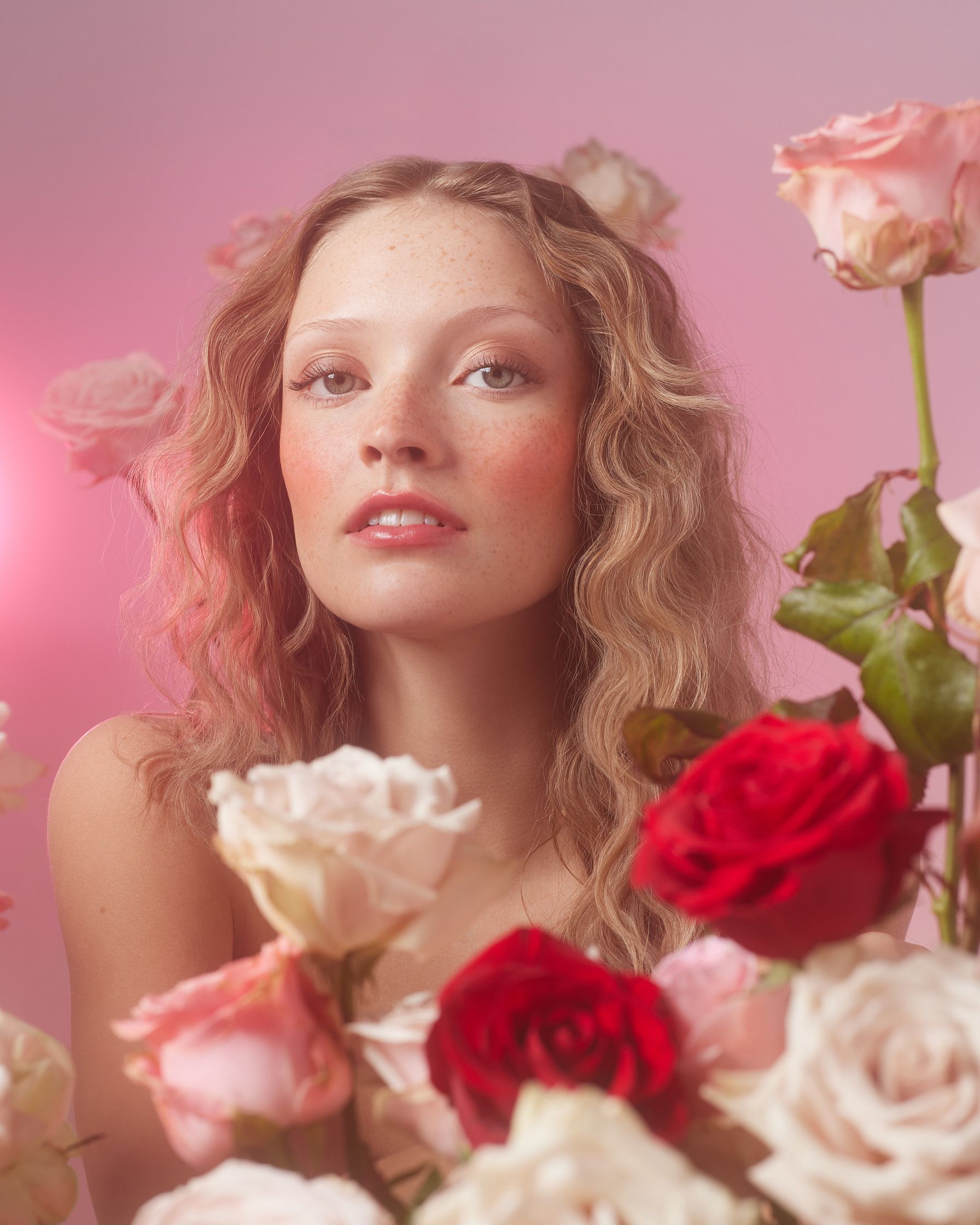 a woman is posing in front of a bunch of roses