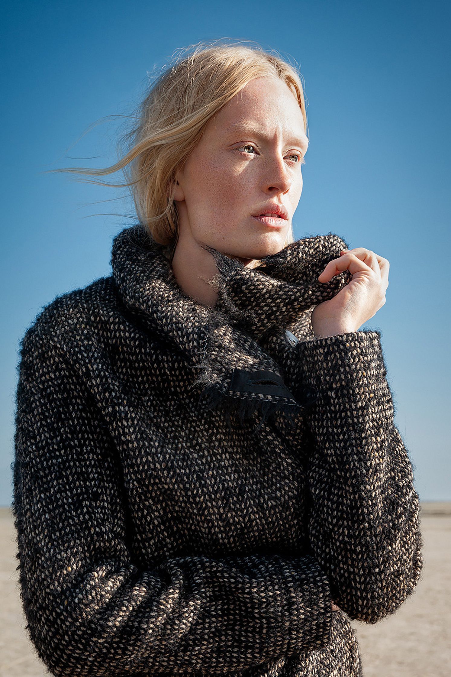 a woman in a black coat standing in the desert retouche advertising campaign