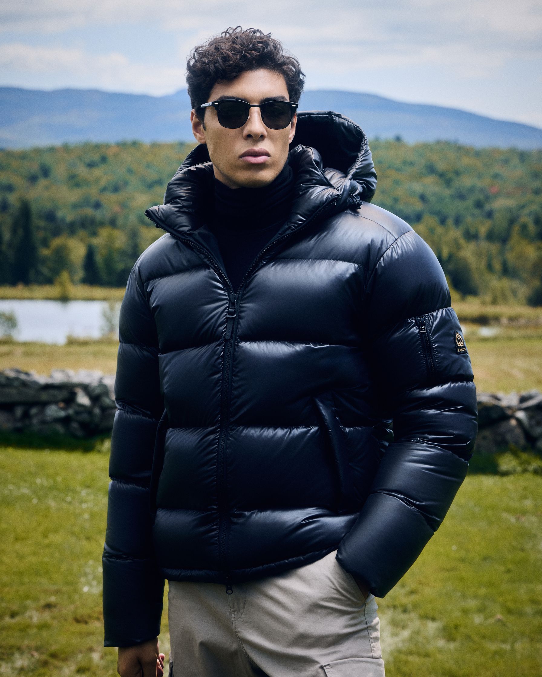 a man in a black puffer jacket standing in a field