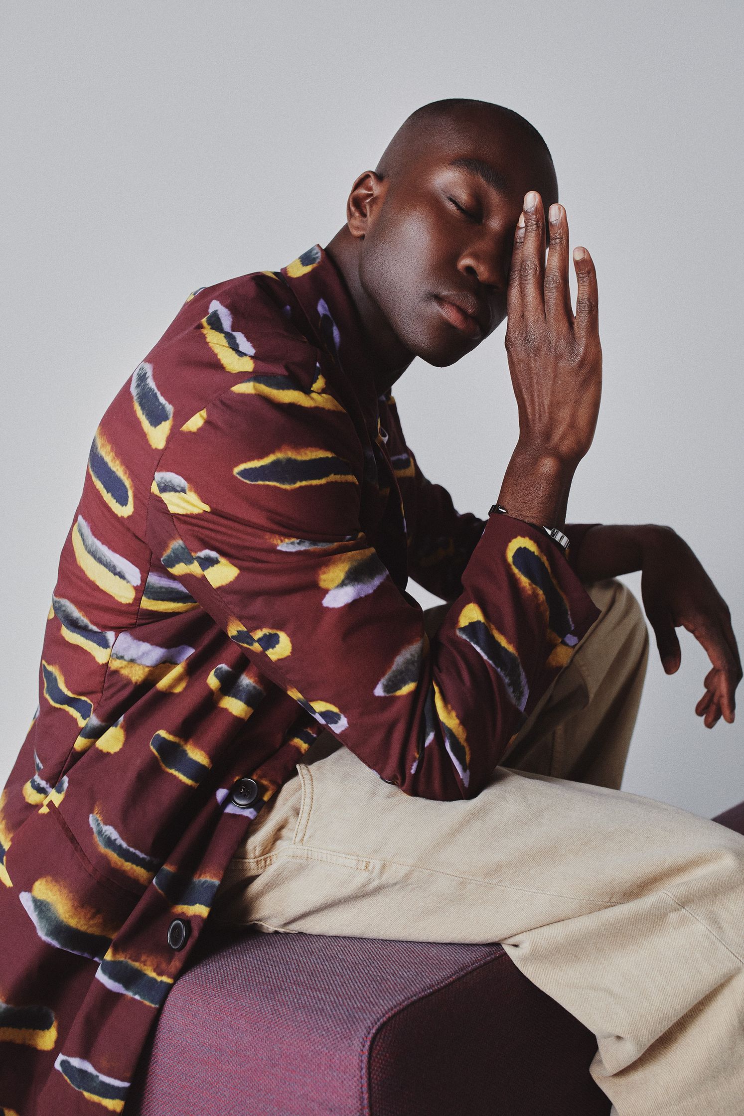 a man sitting on a purple couch with his hand on his face