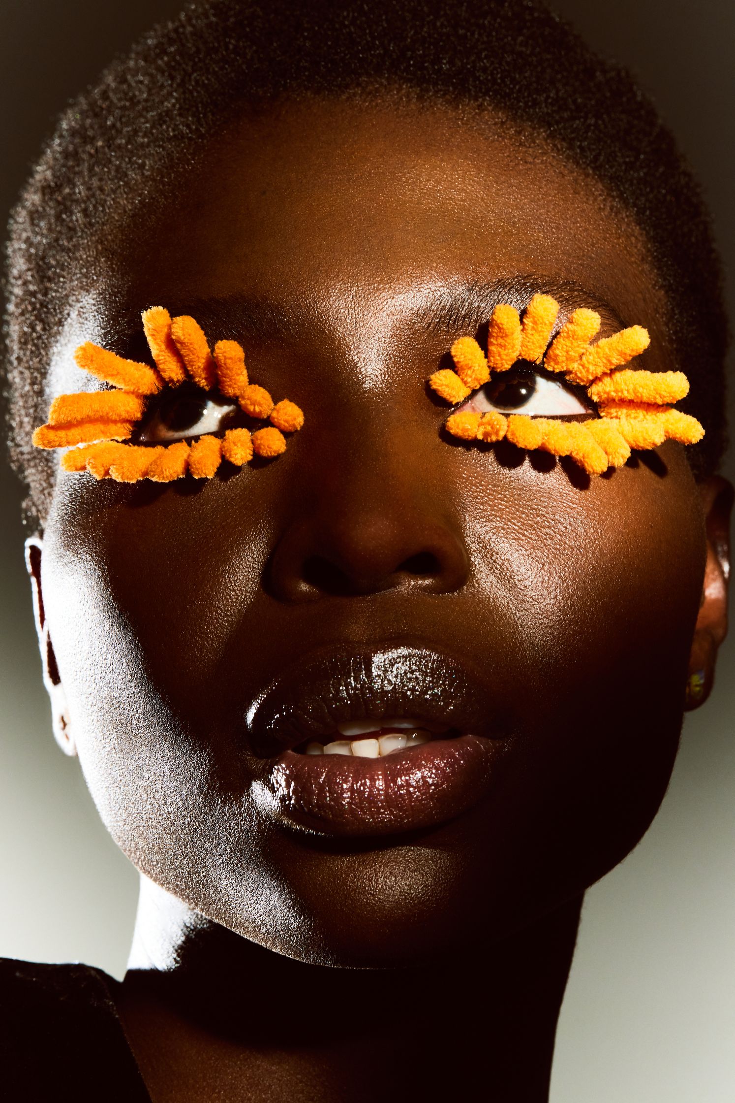 a black woman with orange eye makeup on her face