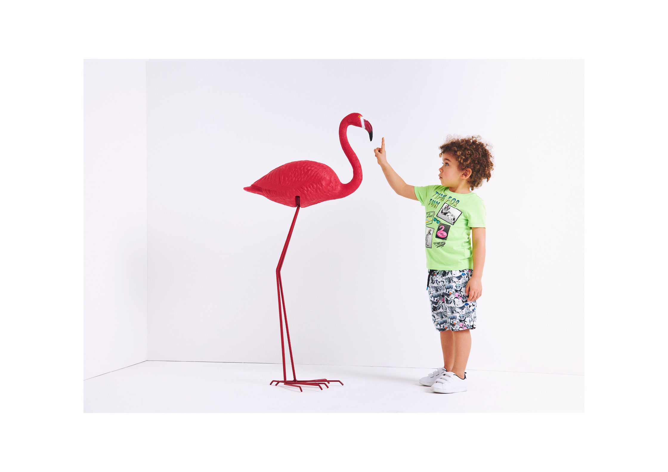 a child is standing next to a red flamingo floor lamp