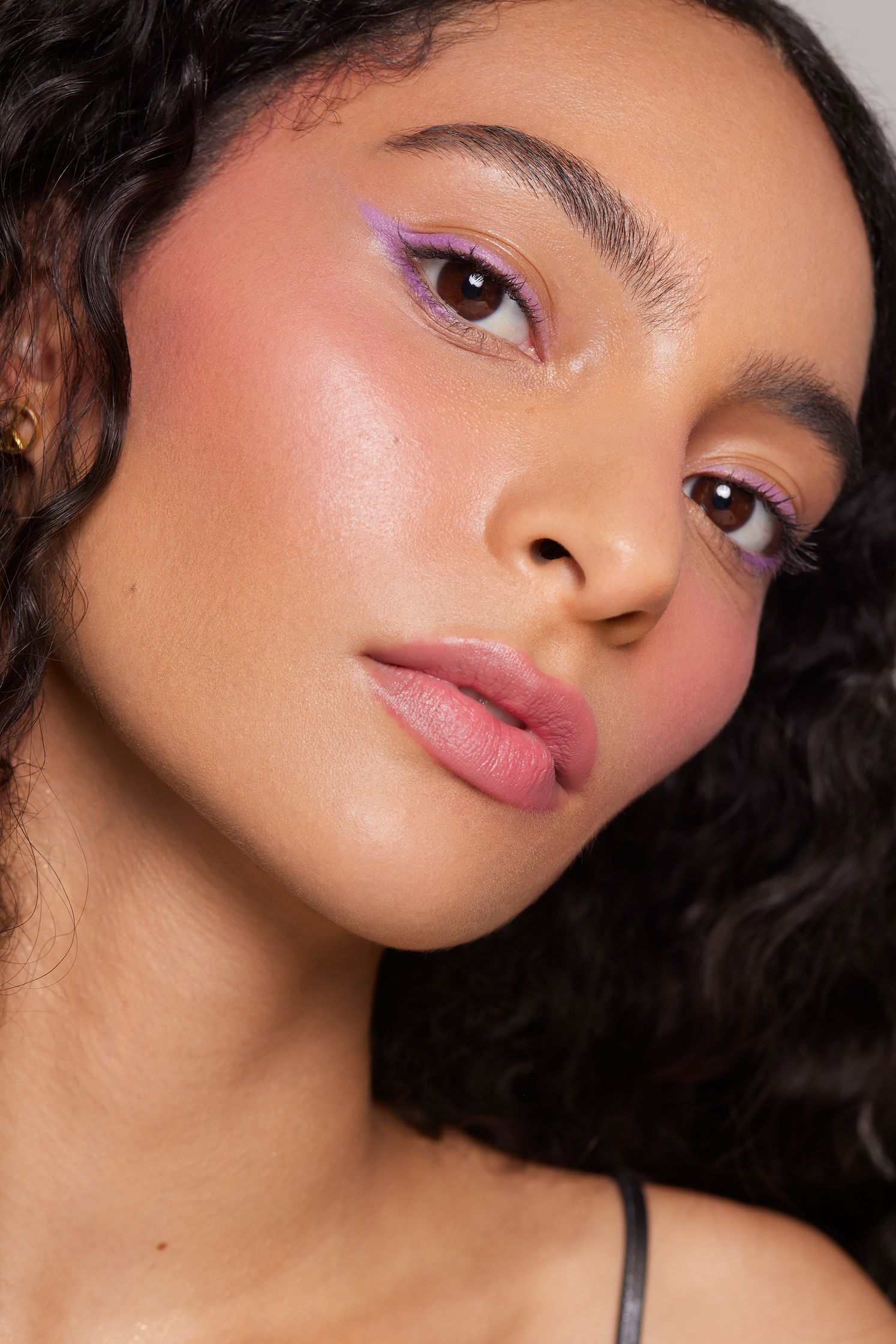 a woman with curly hair and pink eyeshadow