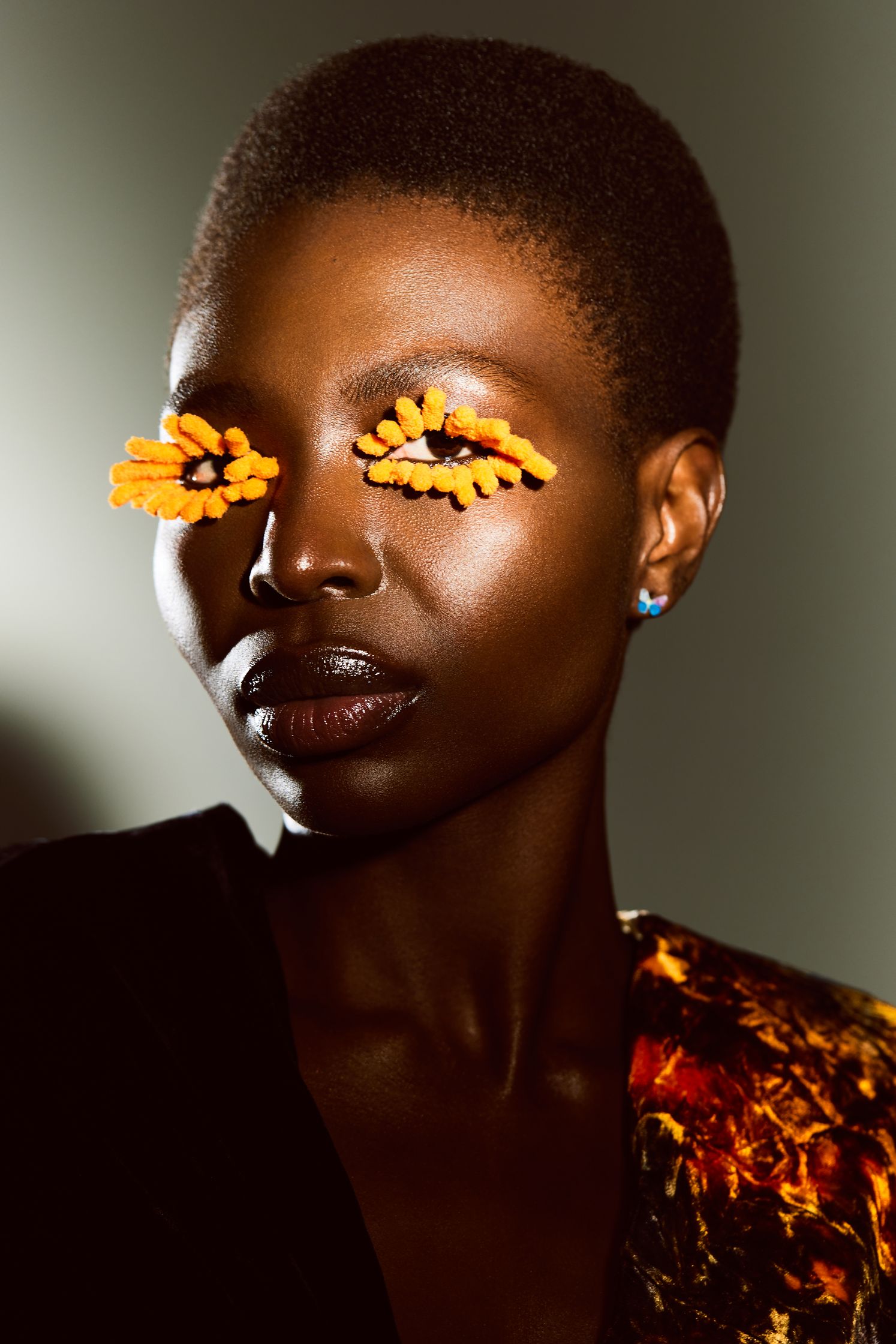 a black woman with orange eye makeup on her face