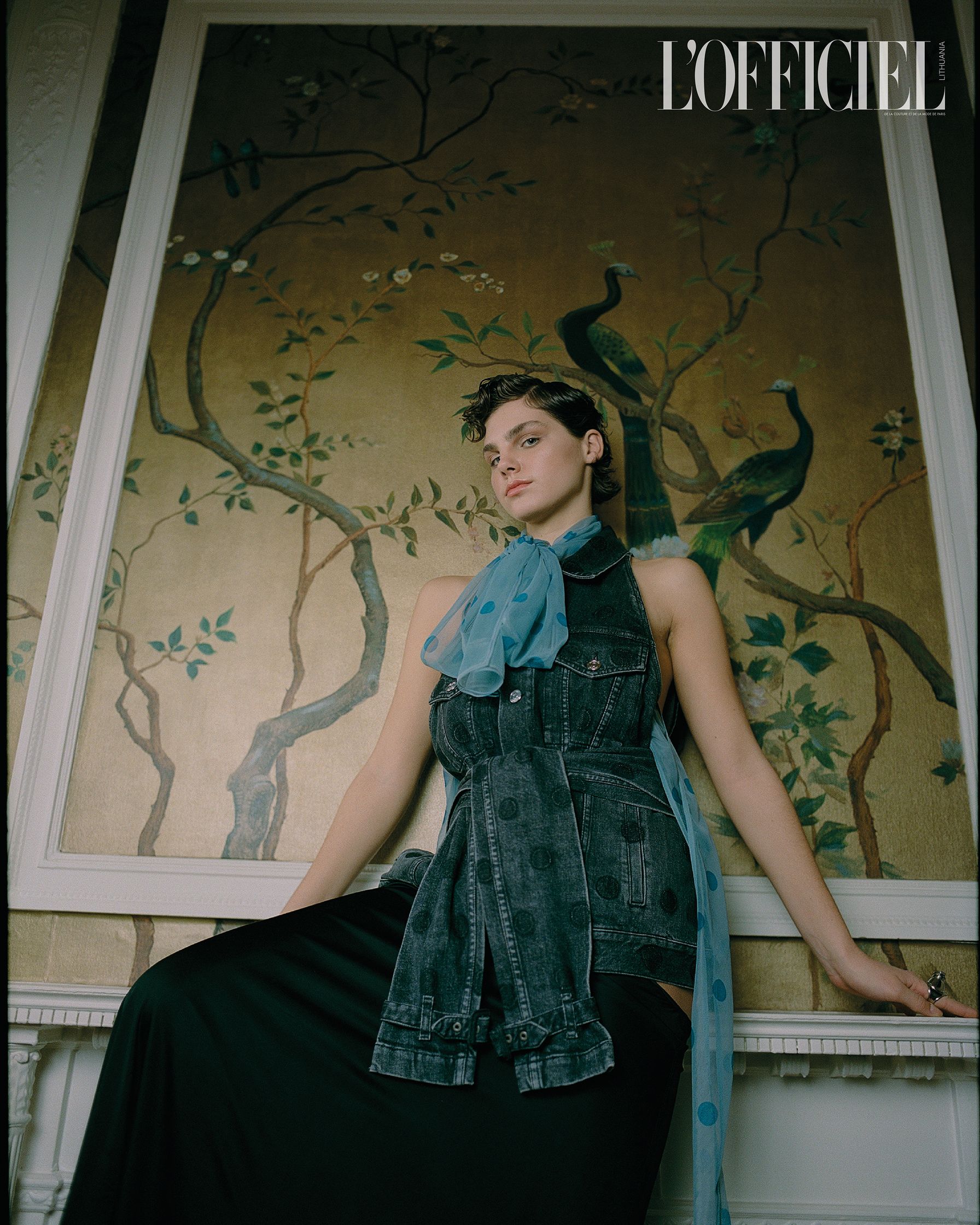 a woman in a blue dress posing in front of a wall