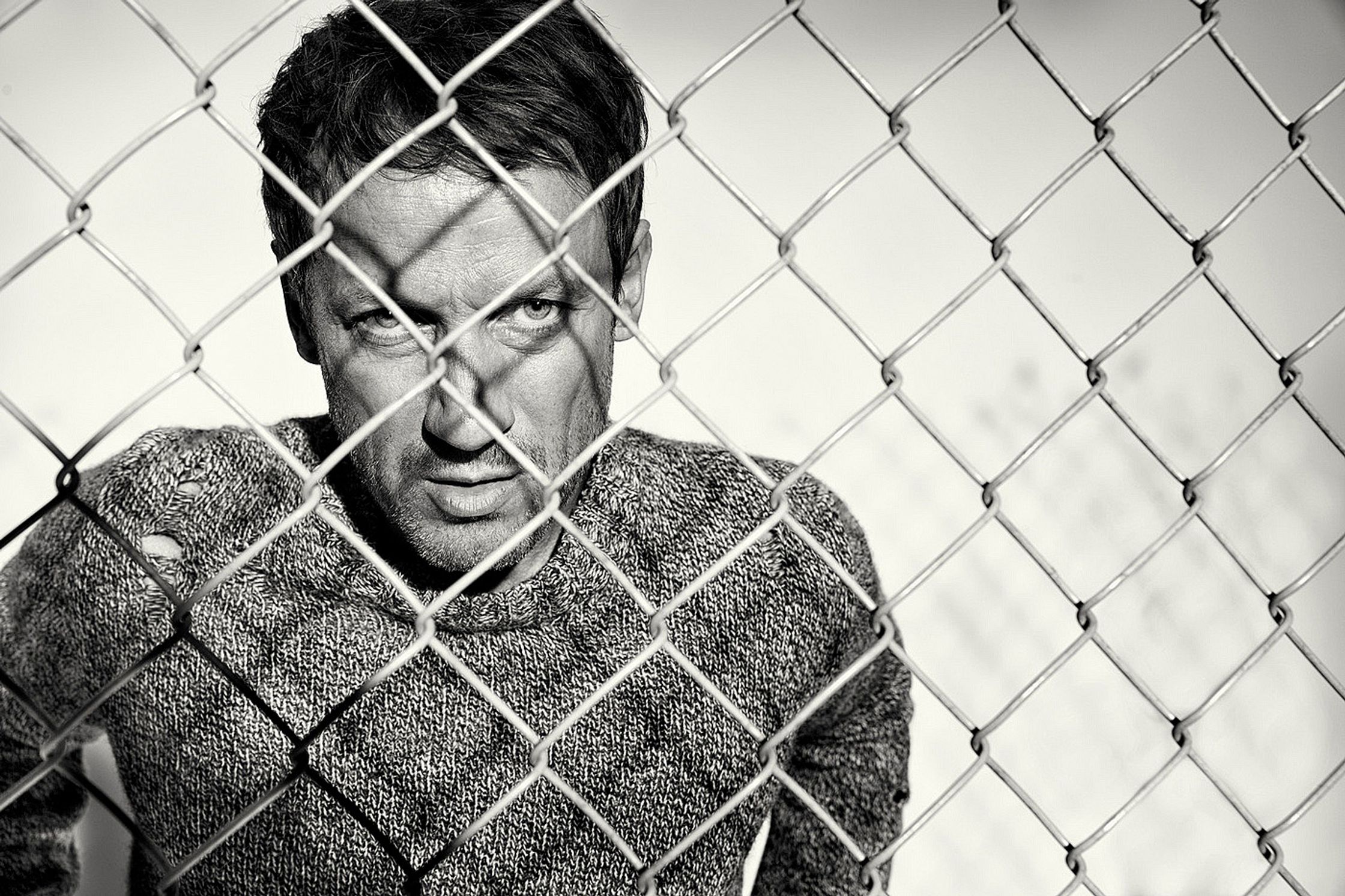 a black and white photo of wotan wilke moehring behind a chain link fence
retusche by glamtouch