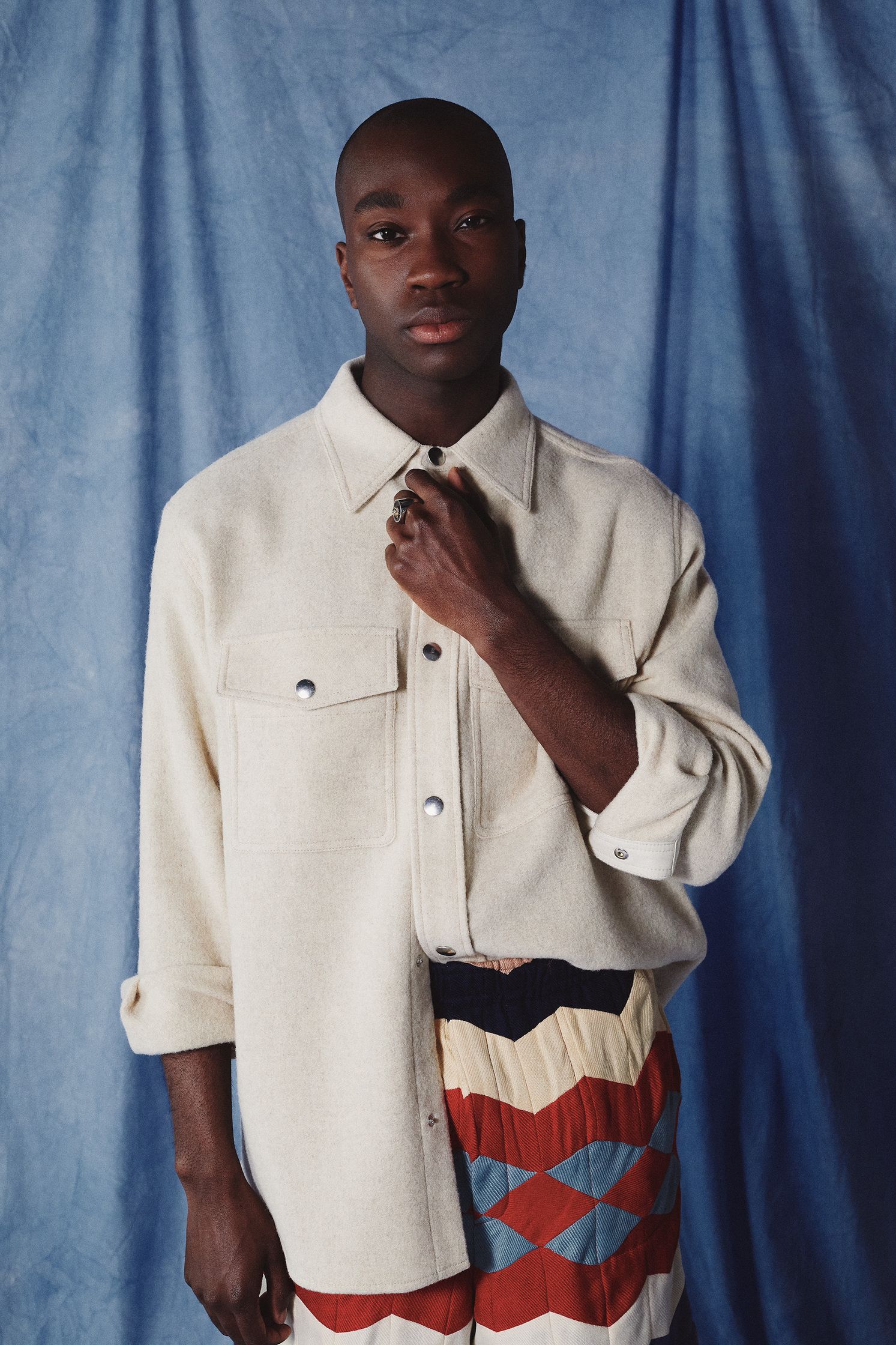 a black man posing in a colorful shirt and pants