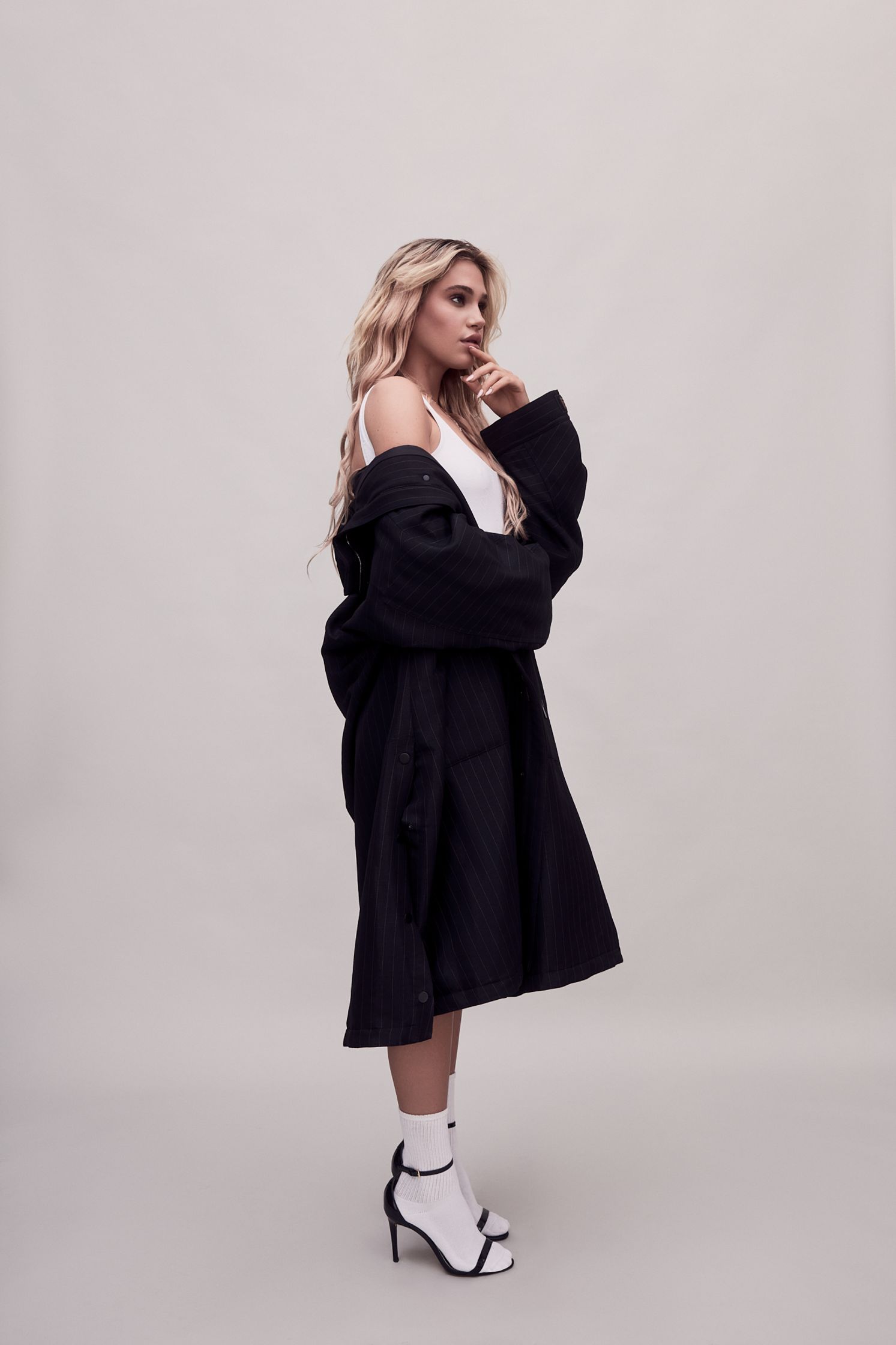 a woman in a black coat posing on a white background