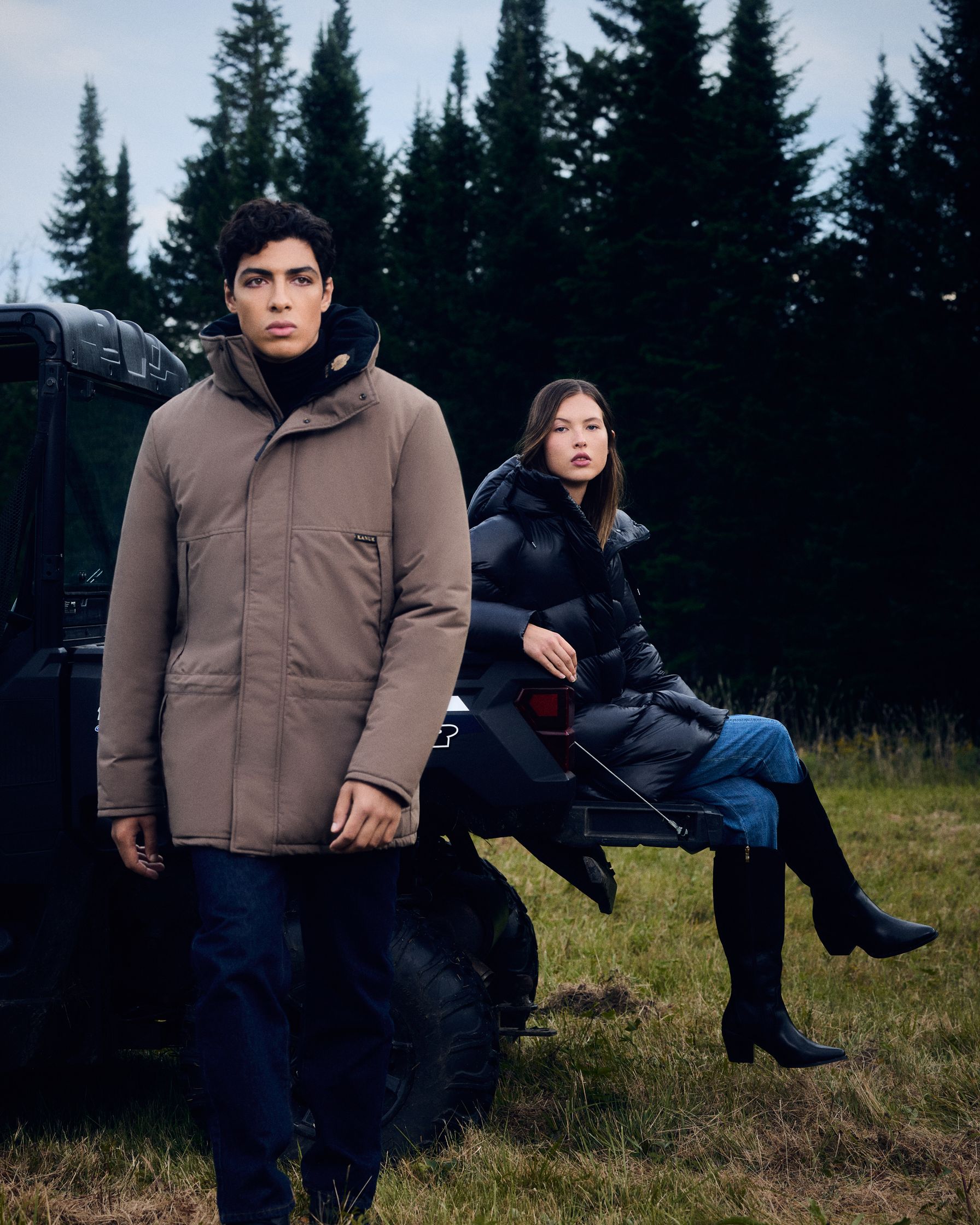 a man and woman standing next to a jeep in a field