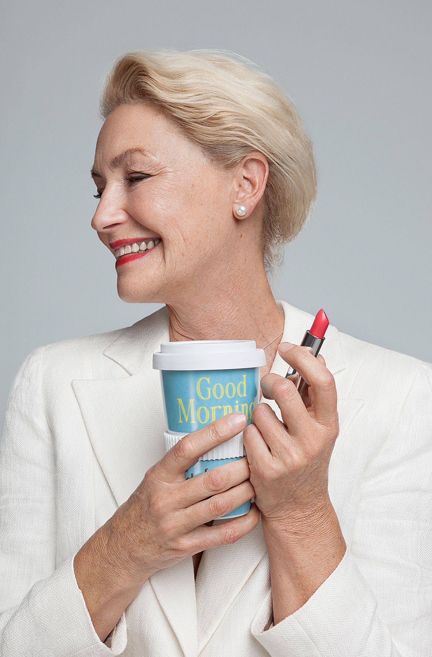 a woman holding a cup of coffee and lipstick best ager post production