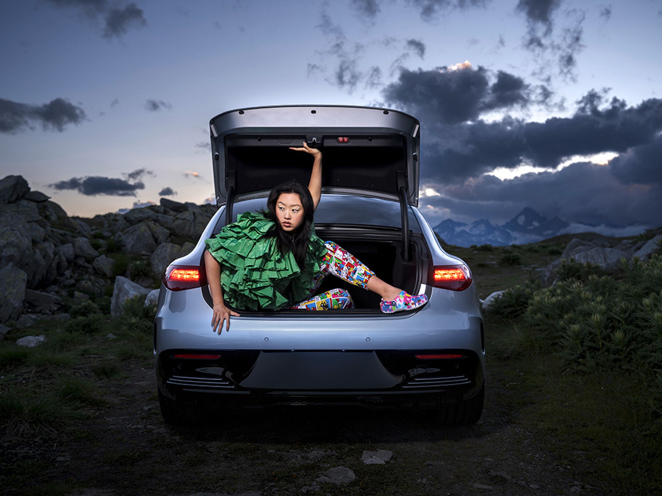 Model Dami J sits in the open trunk of a MERCEDES EQE. She has a bold white graphic liner for makeup. Hair and makeup by Denise Dedich.