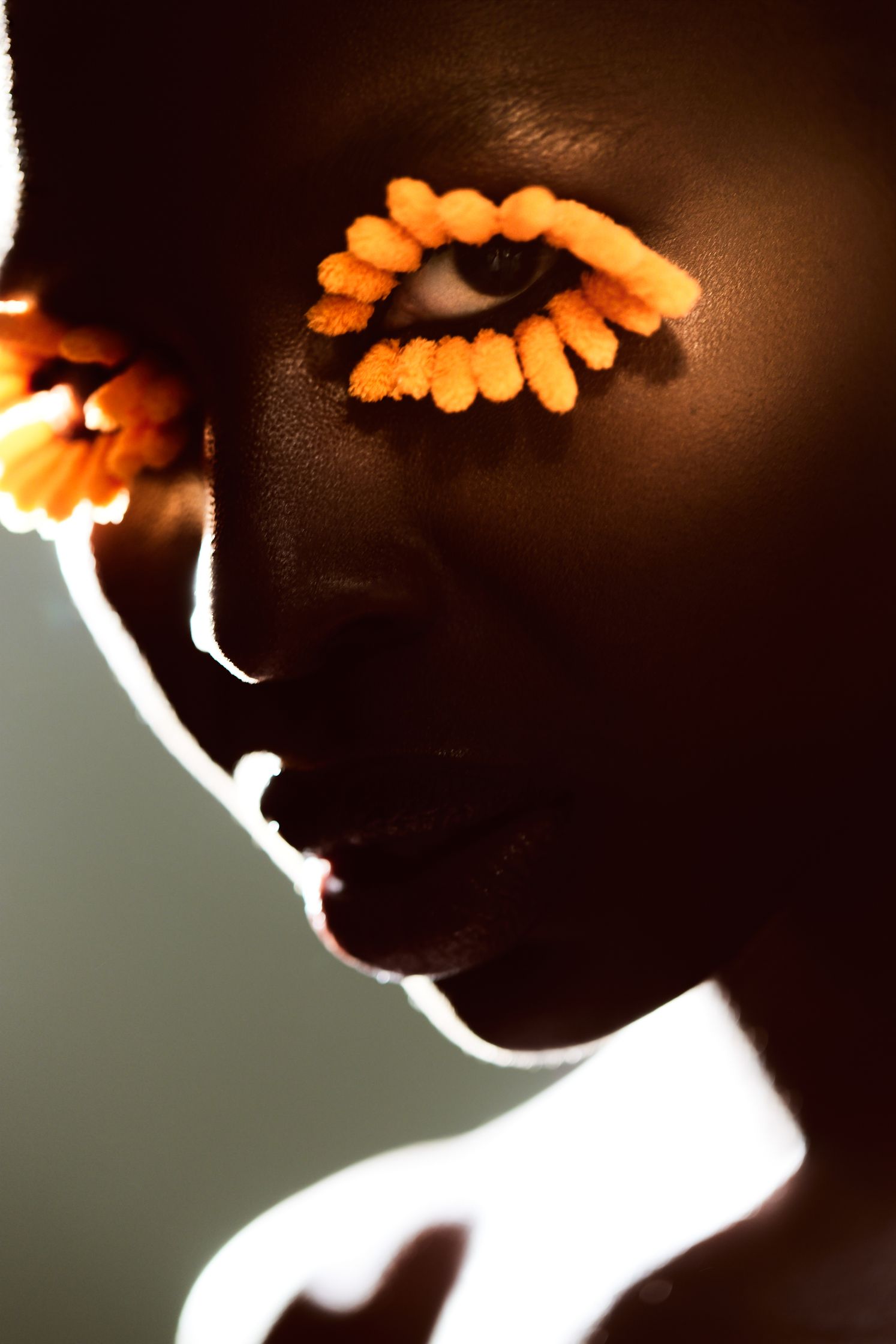 a black woman with orange flowers on her eyes