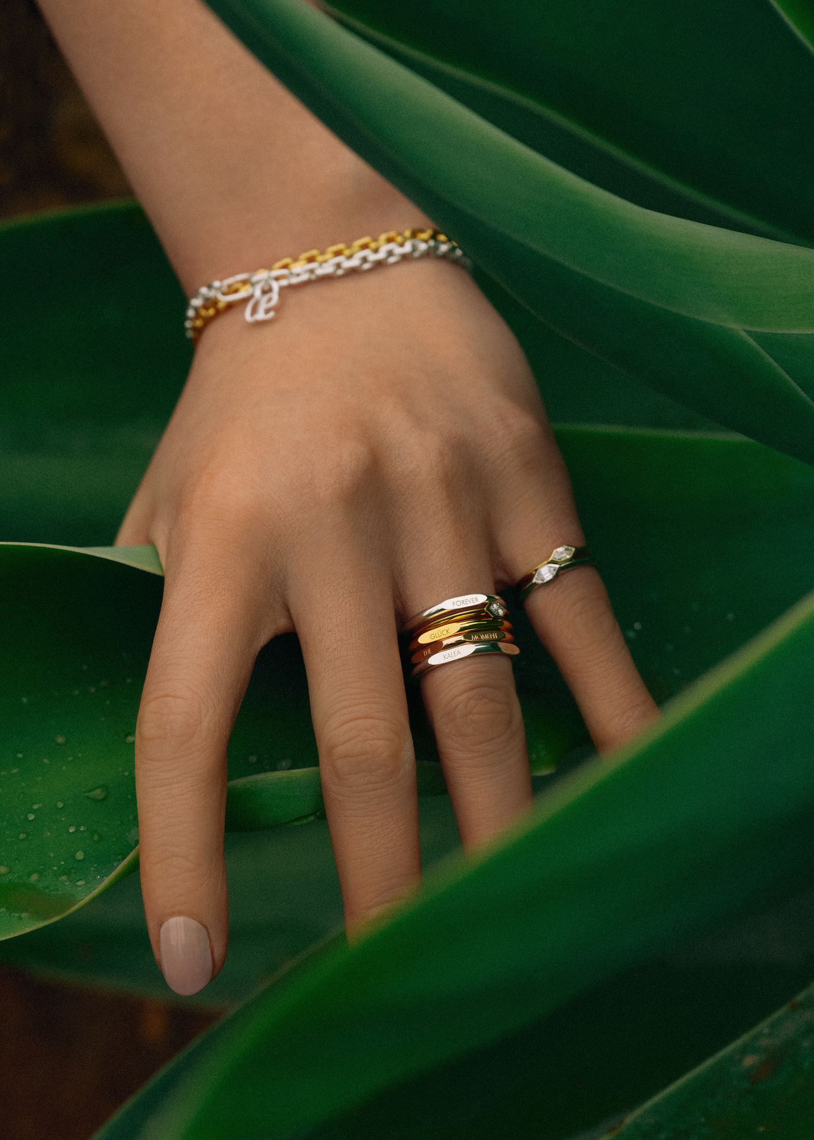 a woman's hand holding a gold ring and a silver ring