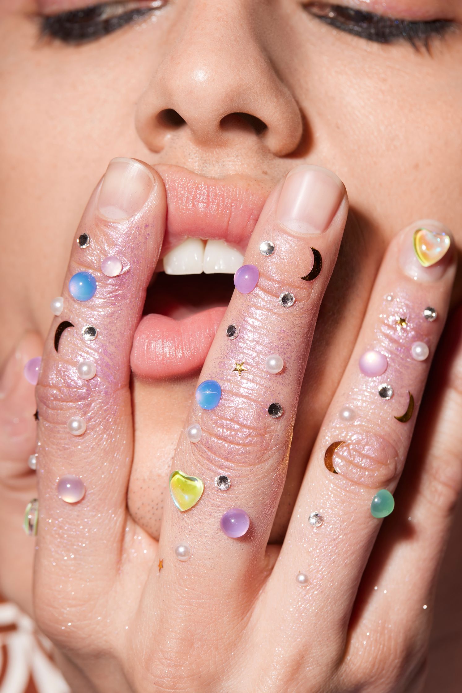 a woman with colorful nails and a moon on her finger