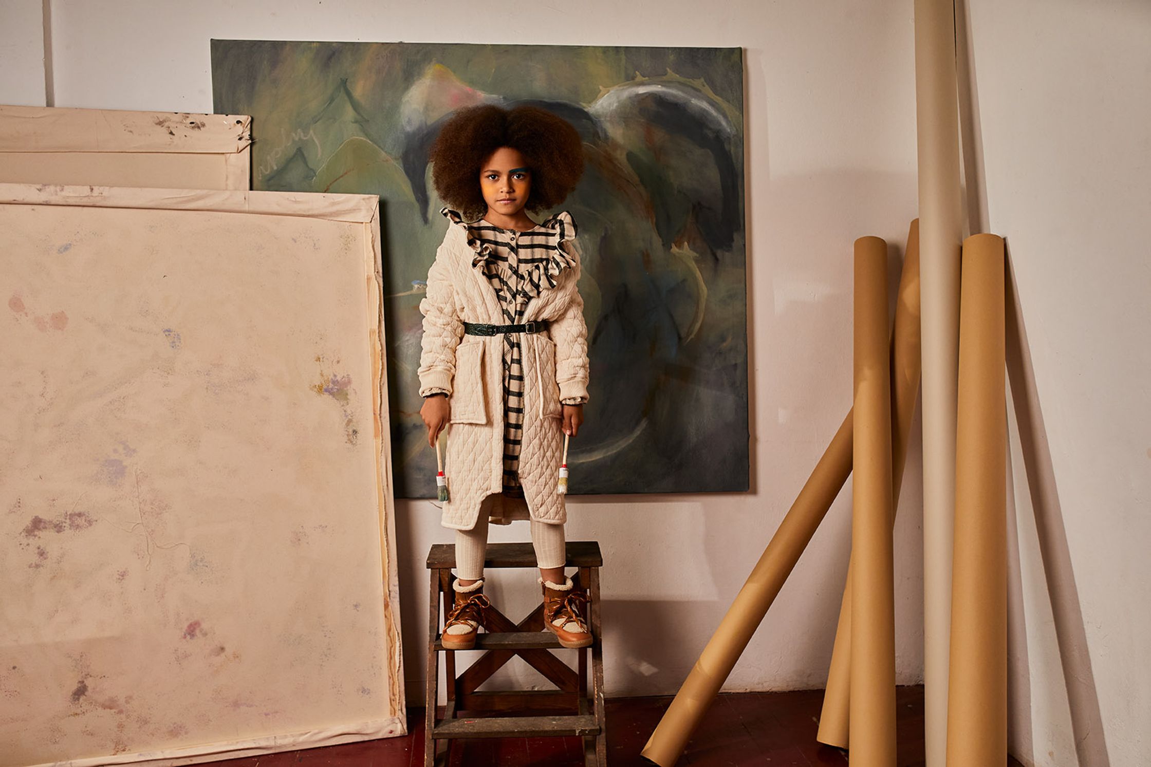 a woman standing on a stool next to a painting