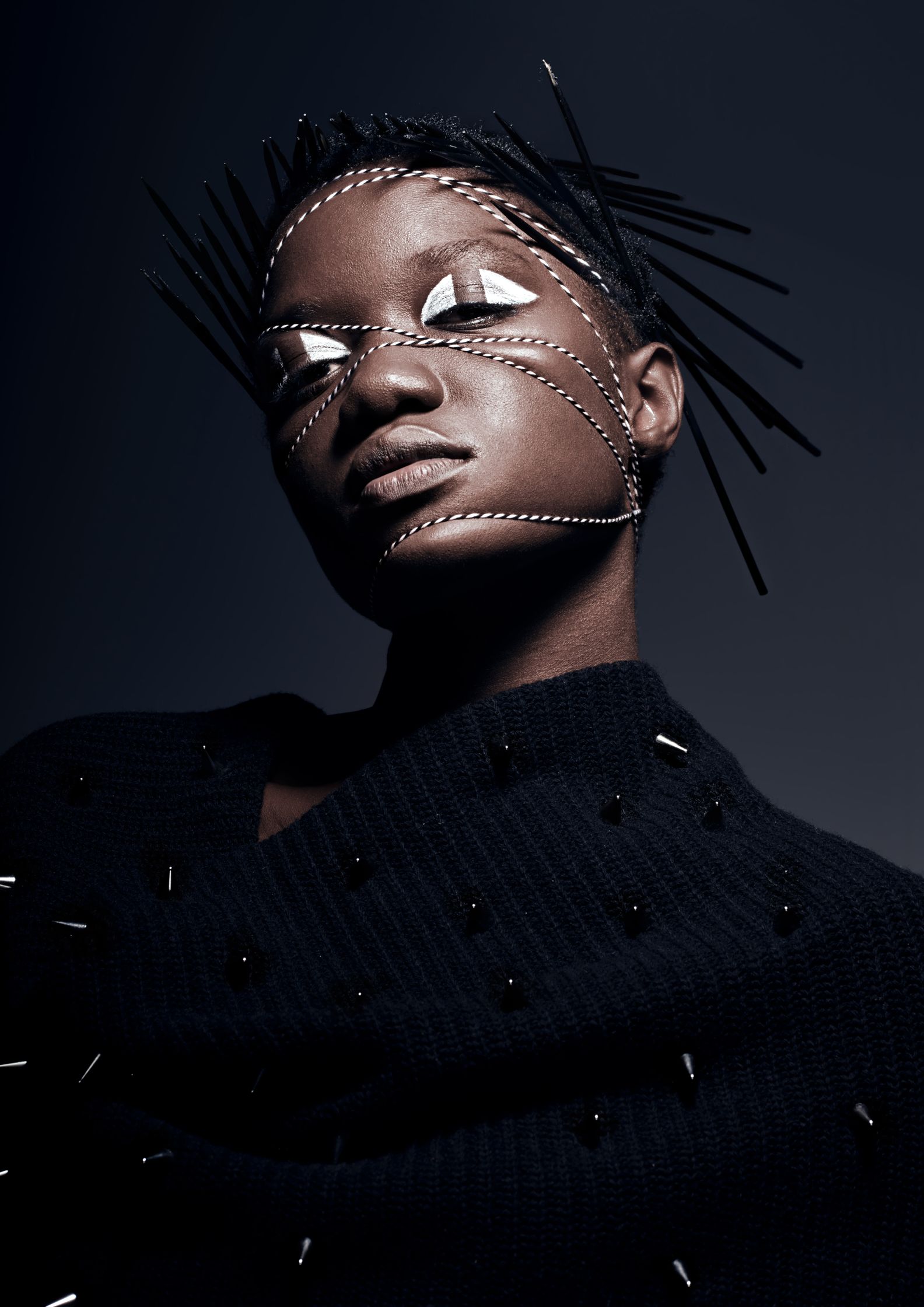 Model adorned with sharp accessories and abstract makeup, exploring futuristic and avant-garde beauty