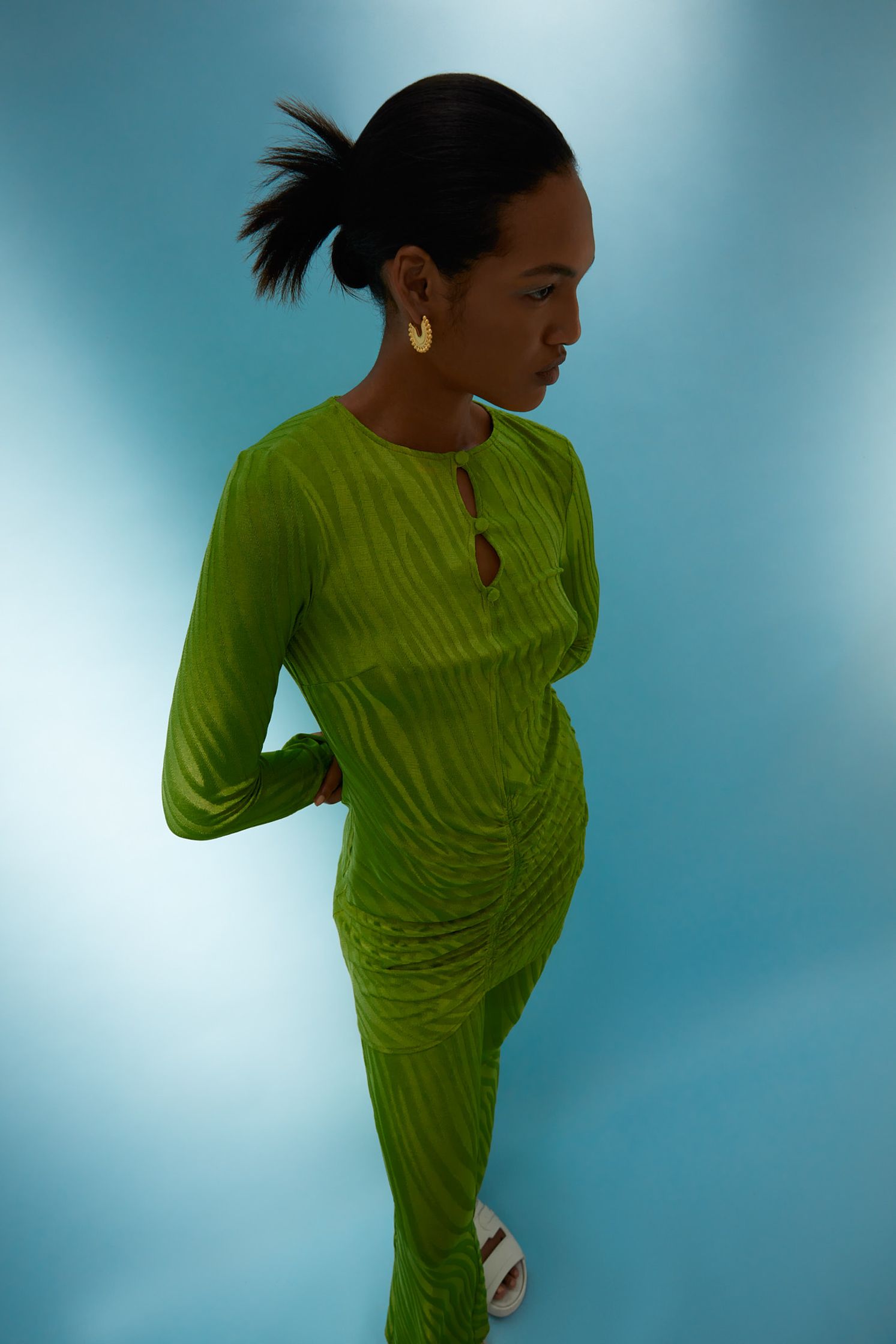 a woman in a green dress standing on a blue background