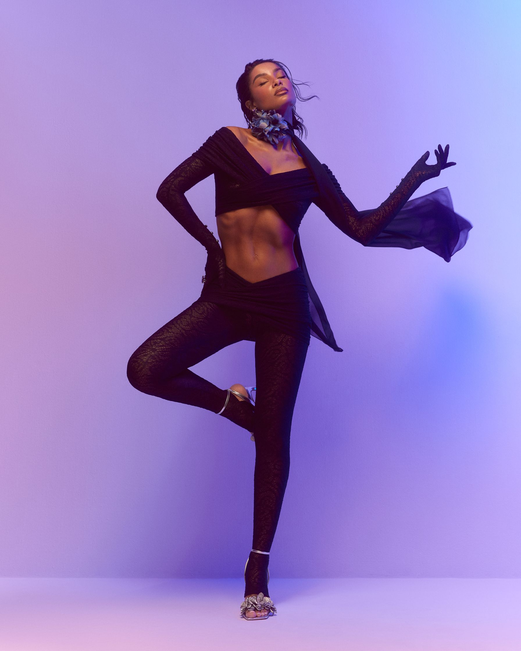 a woman in a black outfit posing on a purple background