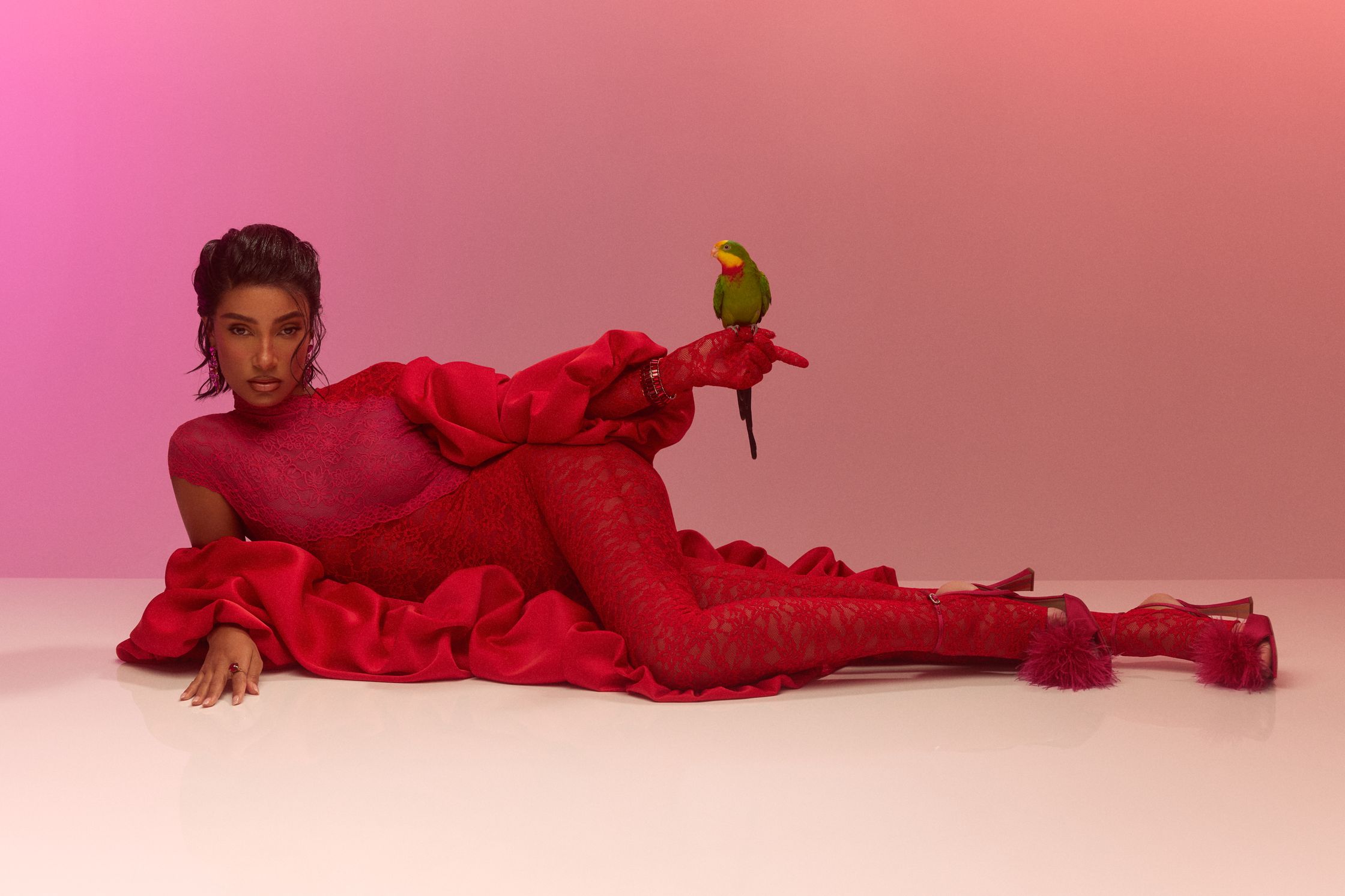 a woman in a red dress posing with a parrot